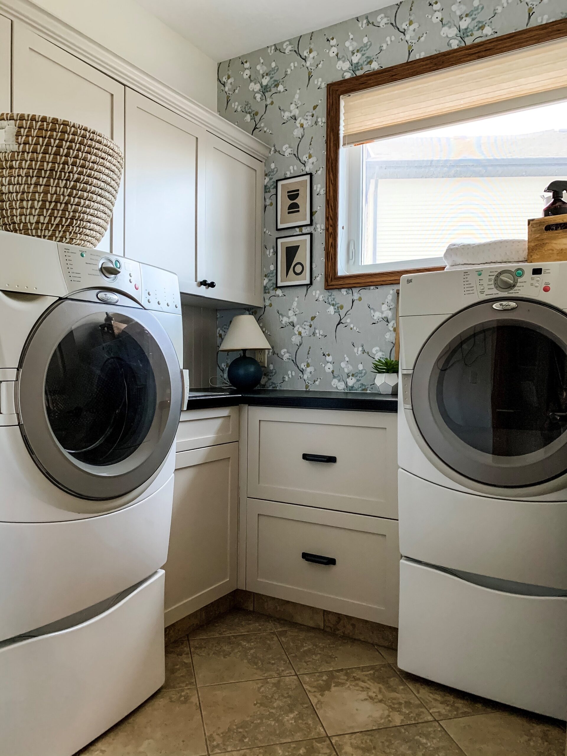 Laundry Room Refresh with painted beige cabinets, black counters, and wallpaper showing some abstract art using fabric and craft paint