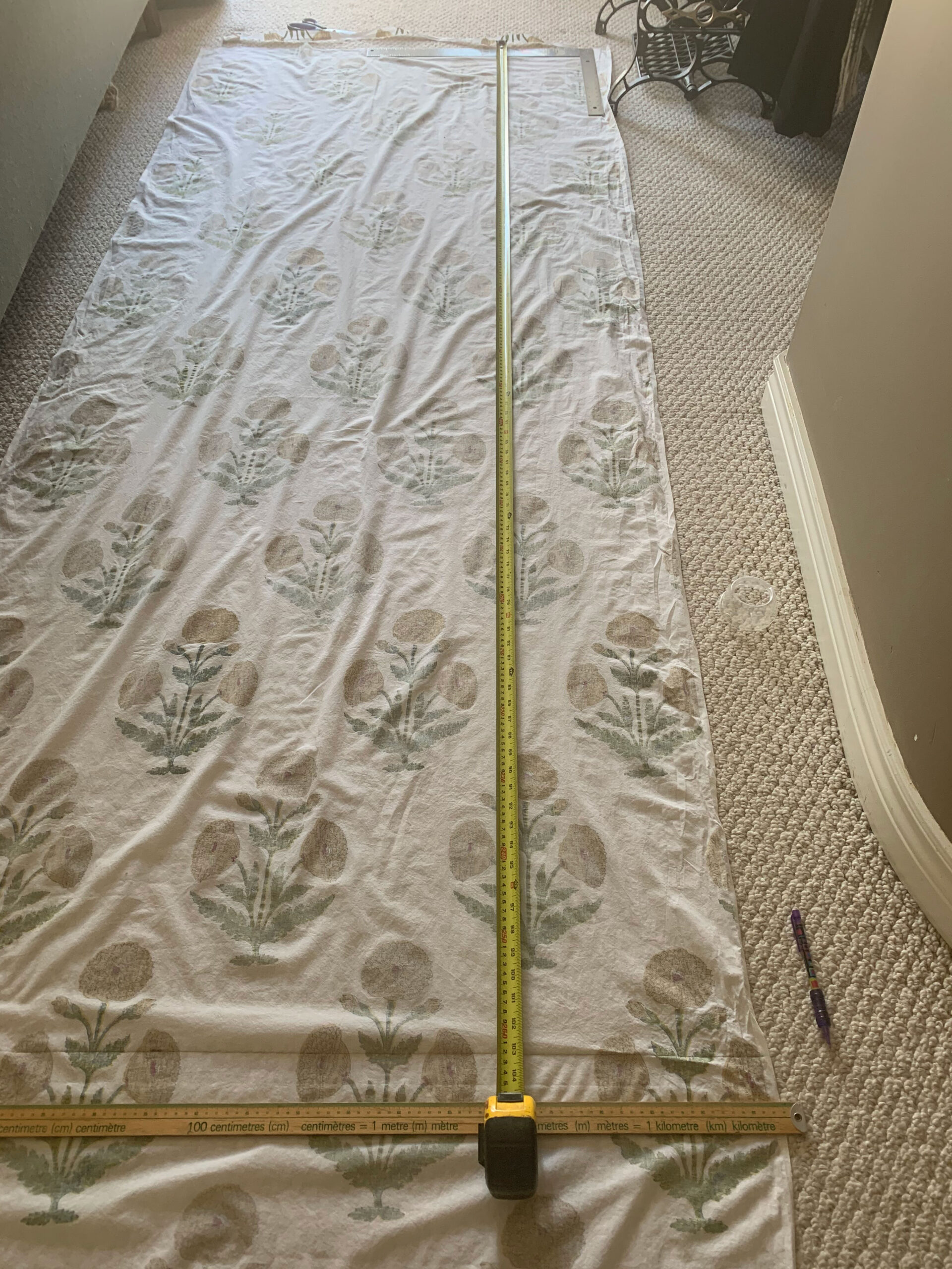 shower curtain fabric laying on floor with measuring tape to mark