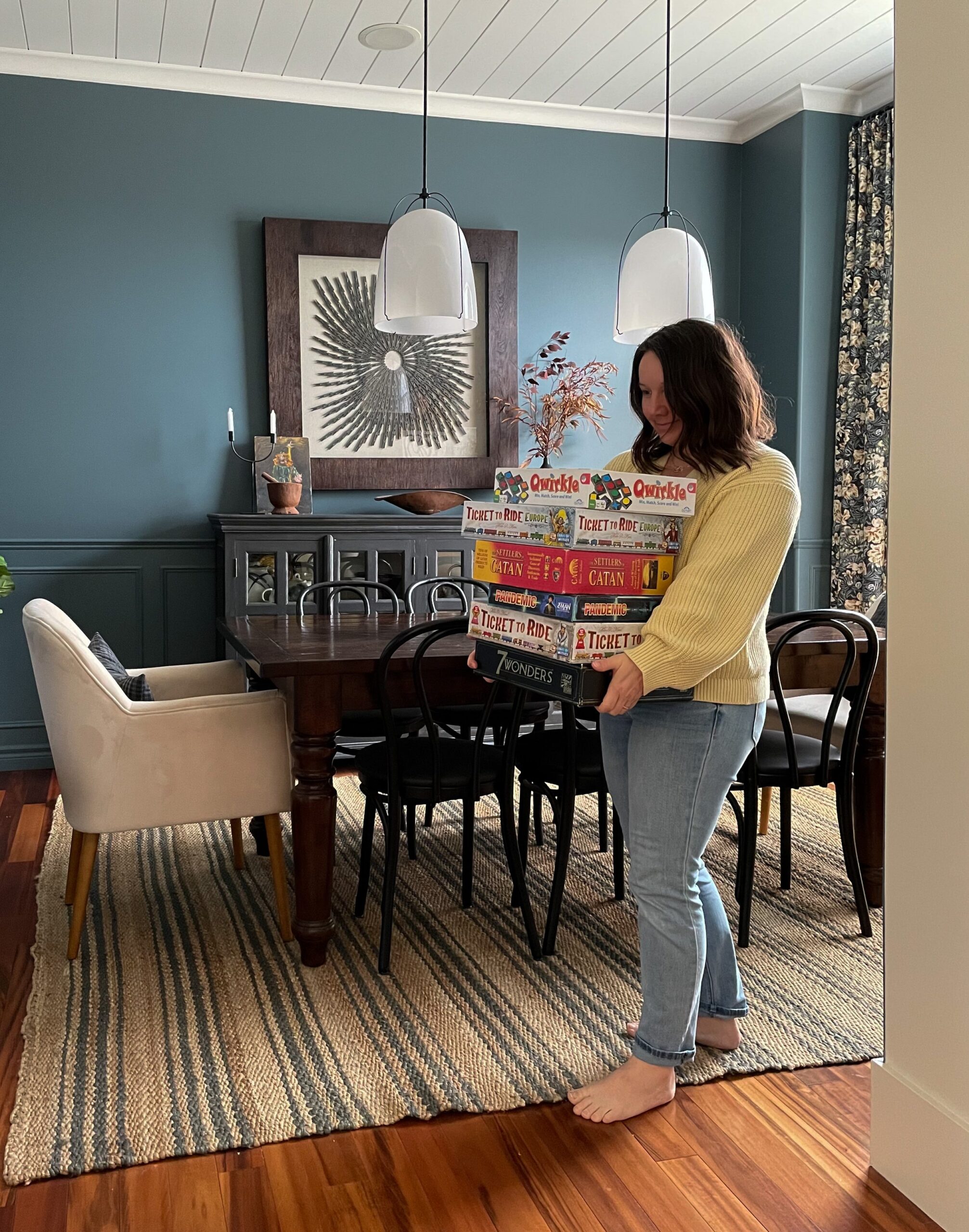 woman carrying game stack in a blue dining room