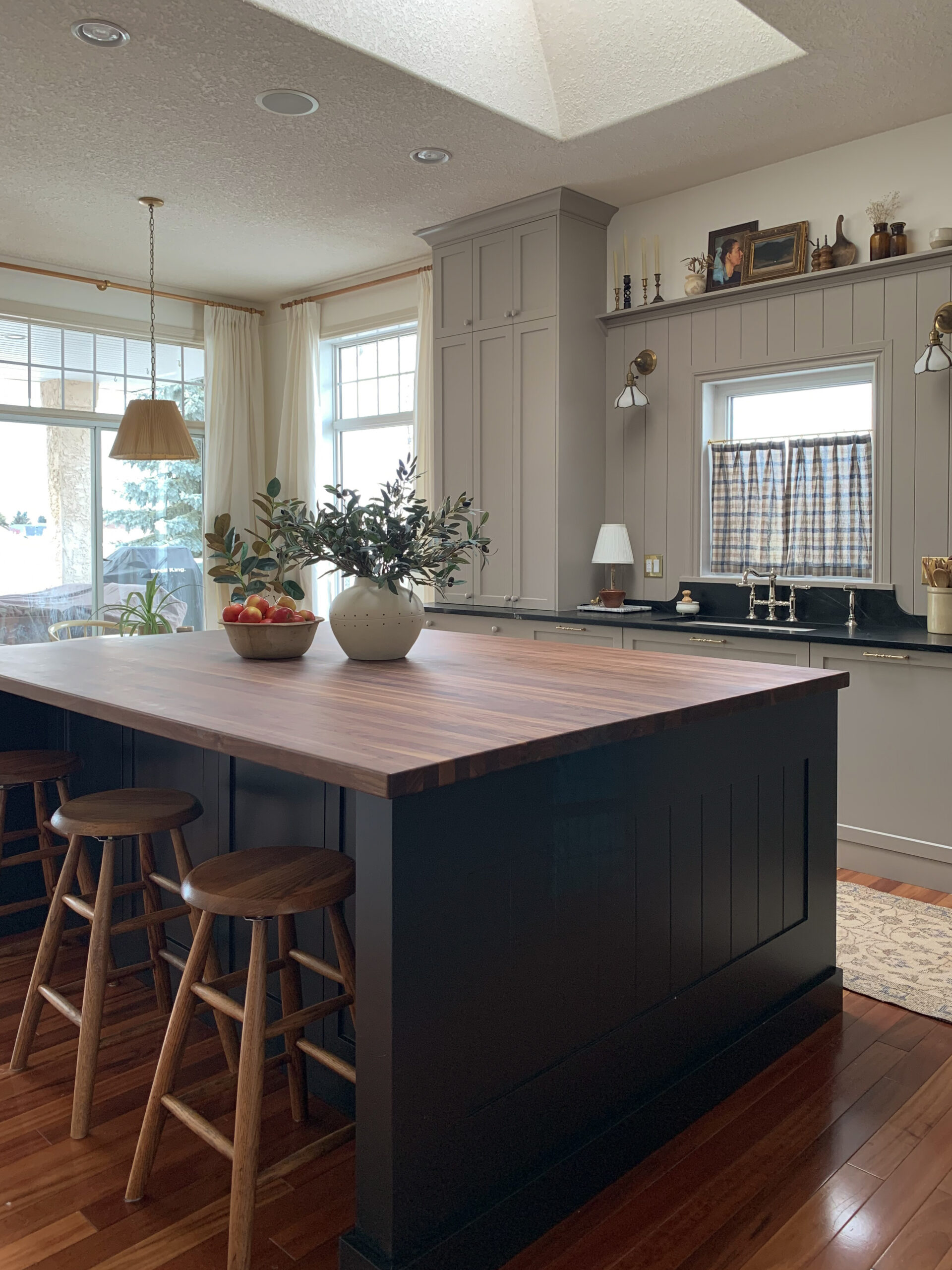 new kitchen with black island, butcher block counters, beige  perimeter cabinets with soapstone counters