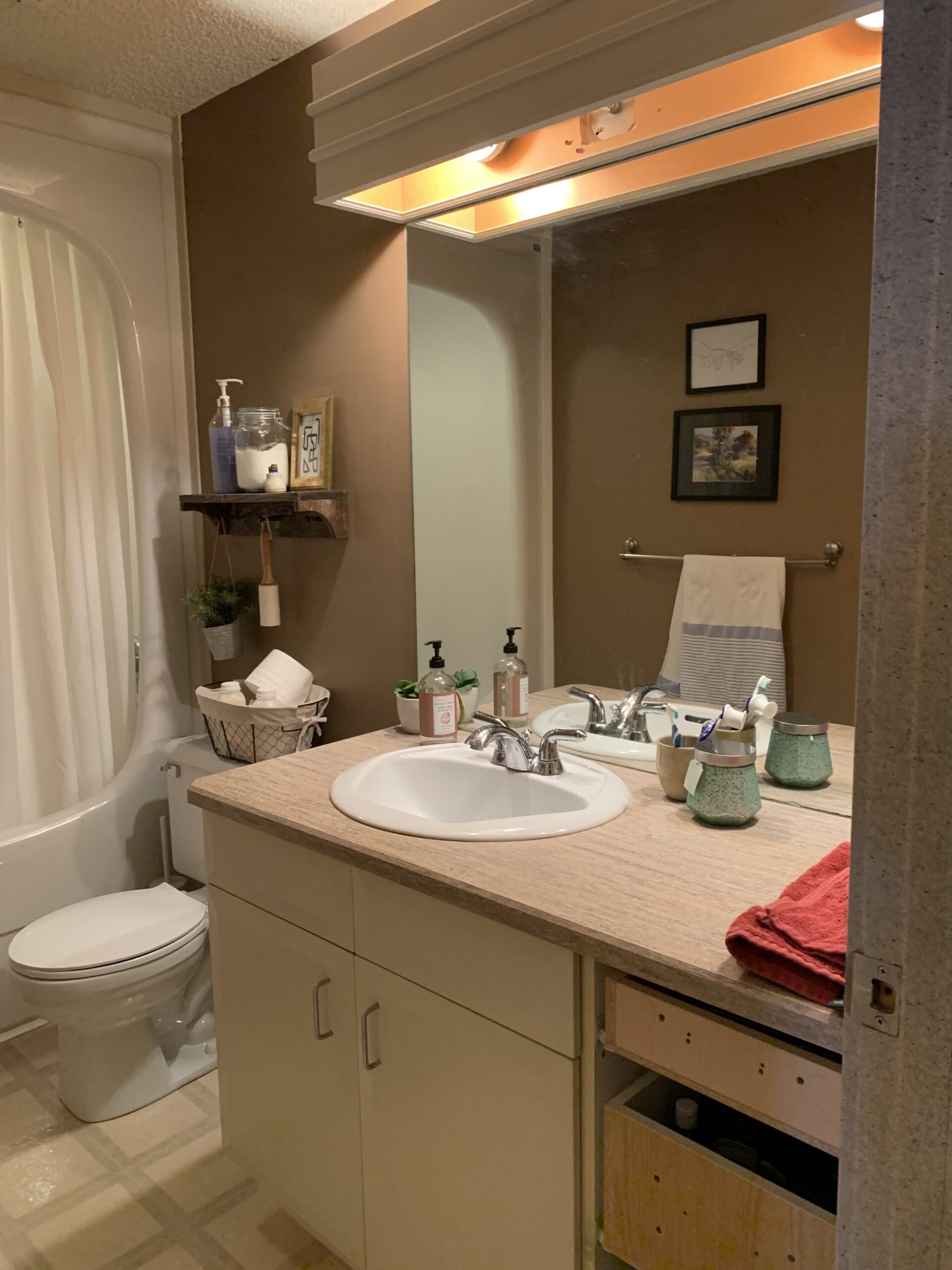 brown bathroom with vantiy with white doors and drawers missing, laminate counters, brown walls
