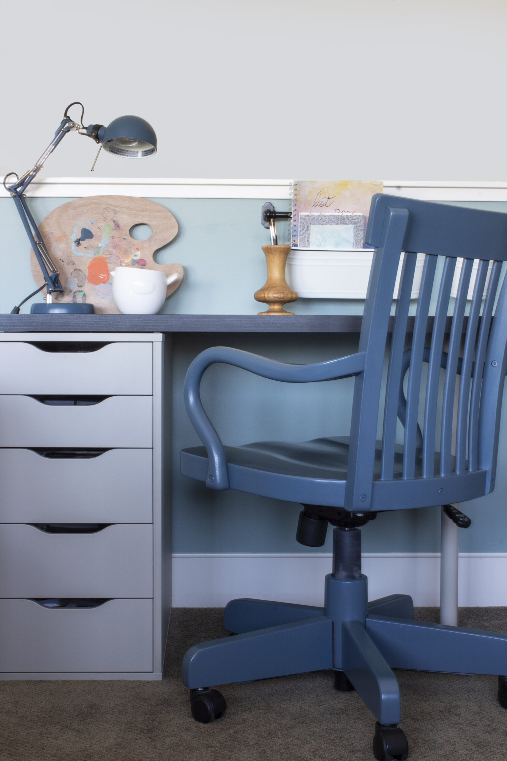 Desk with a blue painted chair, art supplies on des