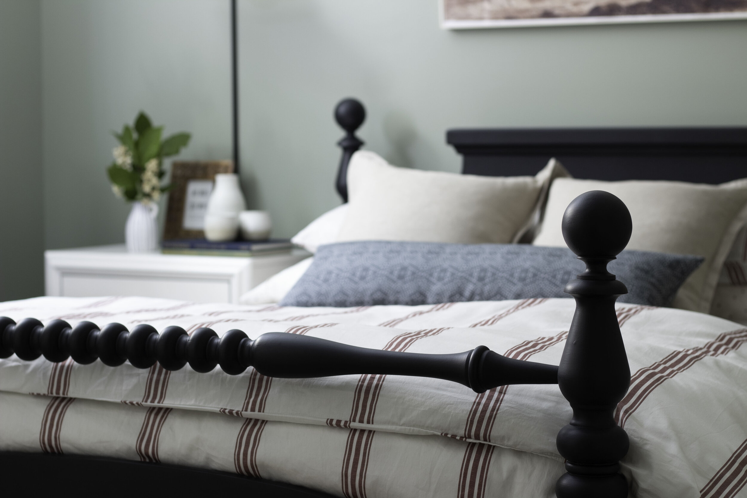 black antique spindle bed with red striped fuvet and blue pillow in a green bedroom