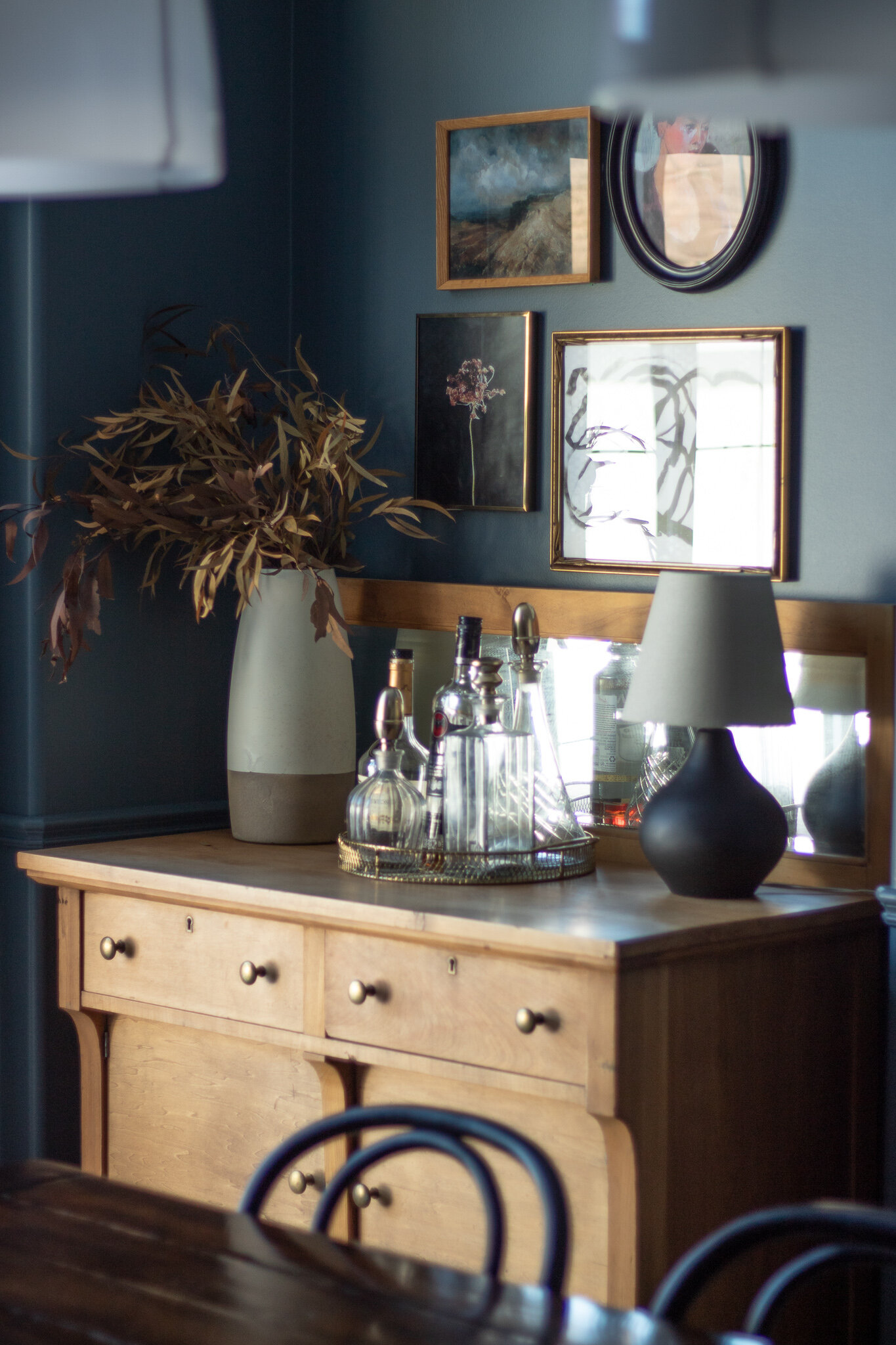 blue room with antique wood buffet server in the corner with bar tray and gallery wall above