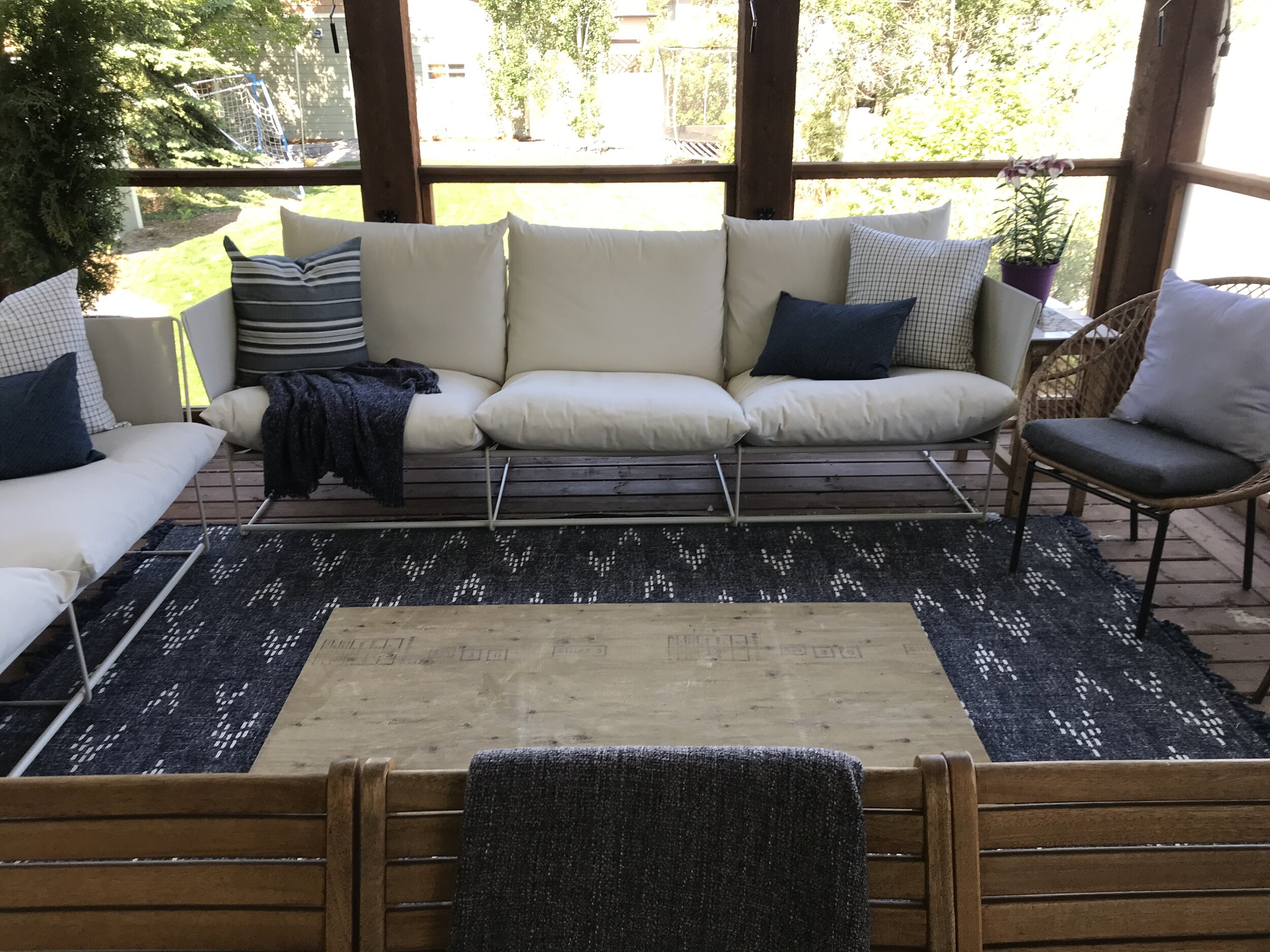 outdoor patio with outdoor couches, blue outdoor rug and a piece of plywood on the ground to get an idea of size