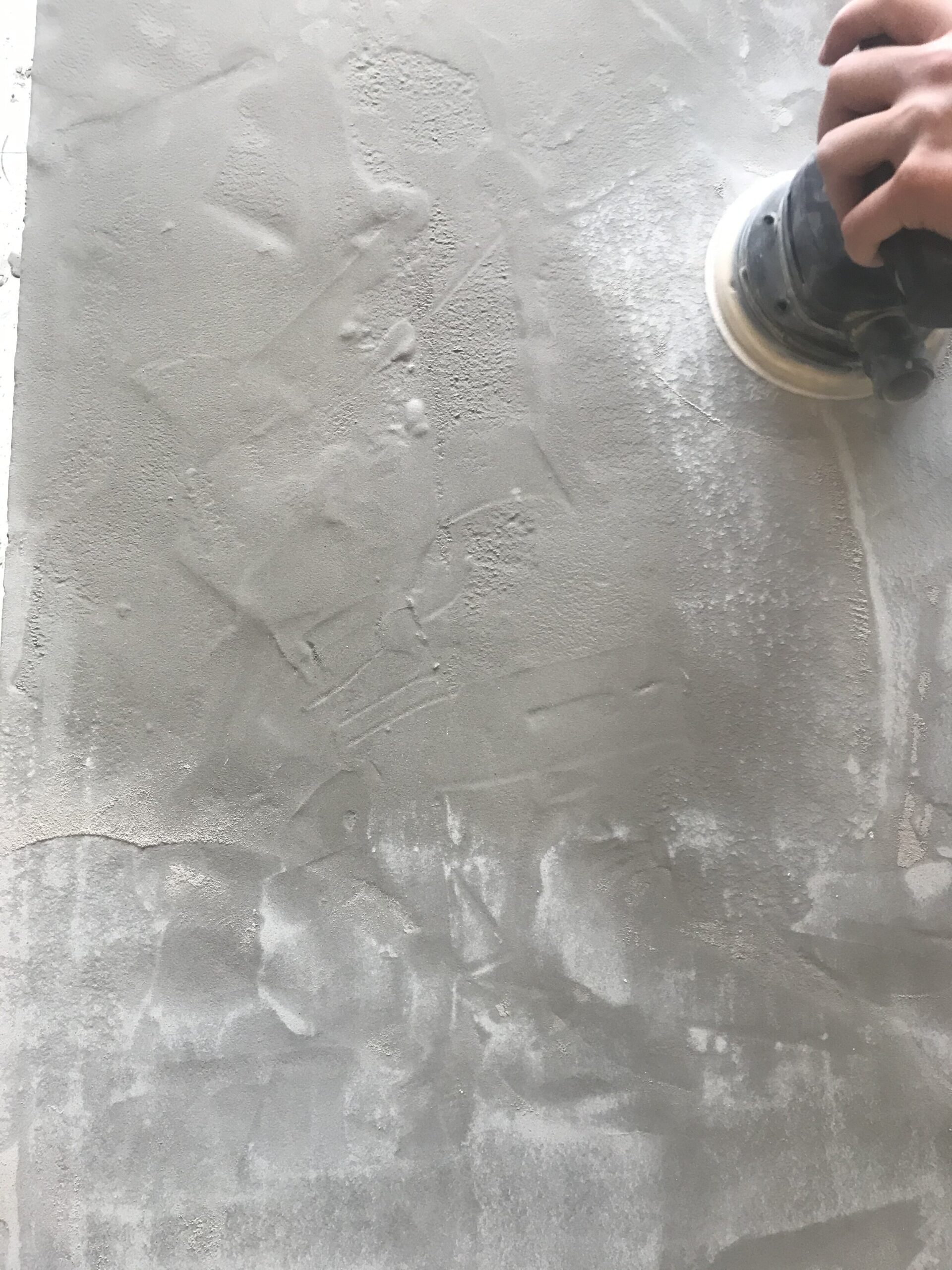 Sanding the top of the self leveling concrete smooth with an orbital sander