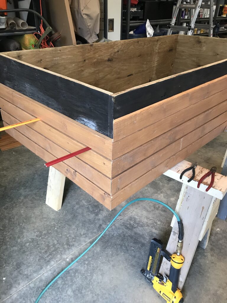 using construction pencils to maintain spacing on slats as they are nailed to the outside of the plywood box