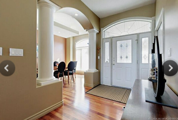 entryway with arched opening into a dining room with large columns on either side, dining room with minimal furniture, brown walls