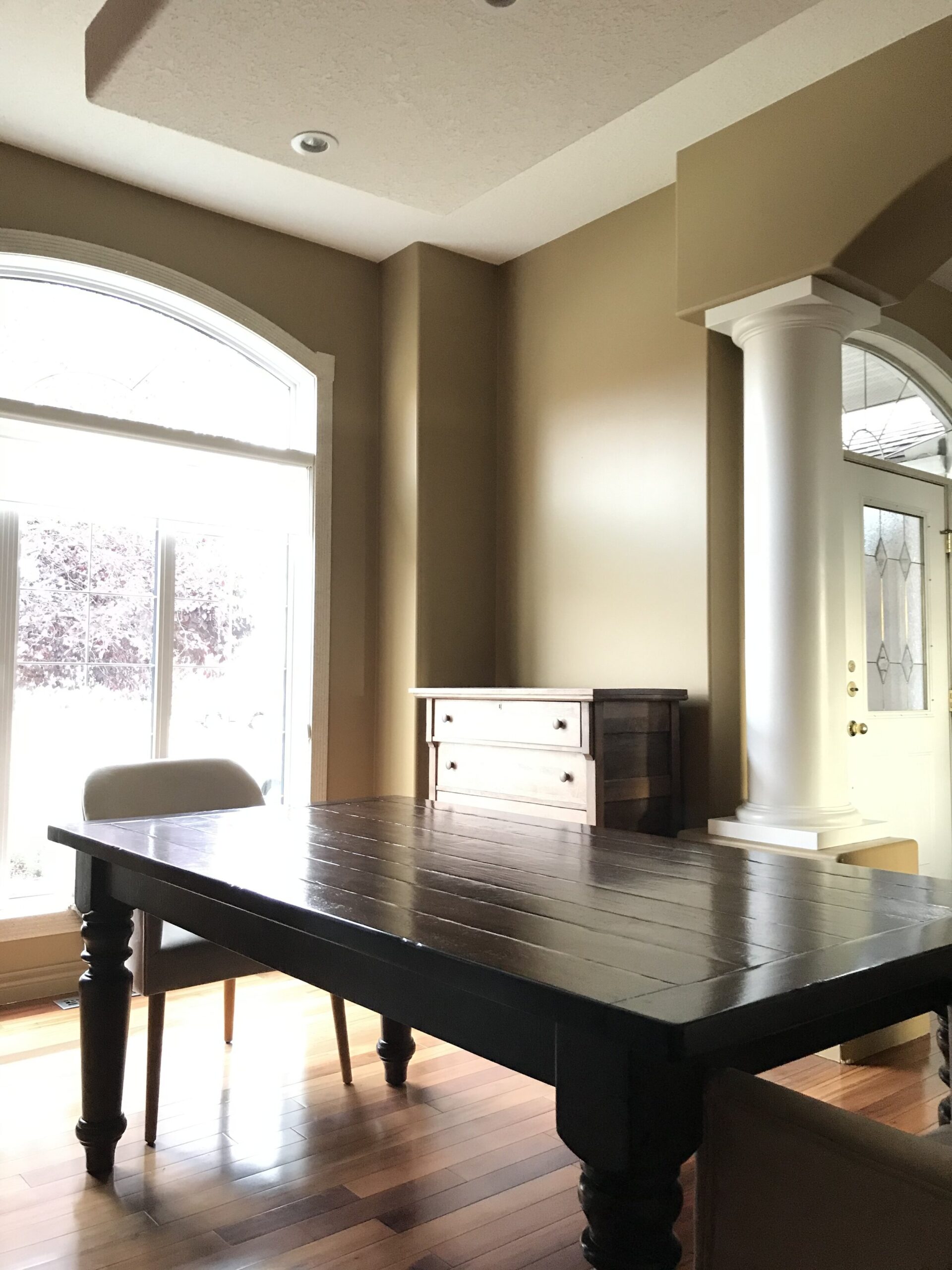 Dining room with columns next to opening, brown walls, wood table and dresser as sideboard