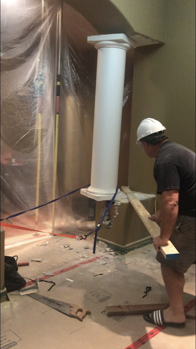man prying out a large column  with a 2x4