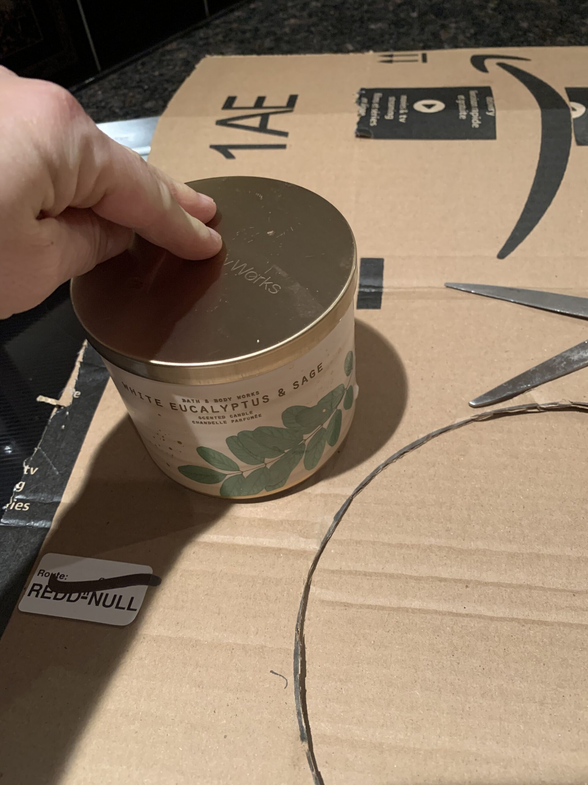 using a candle for a round template to cut a hole in a piece of cardboard