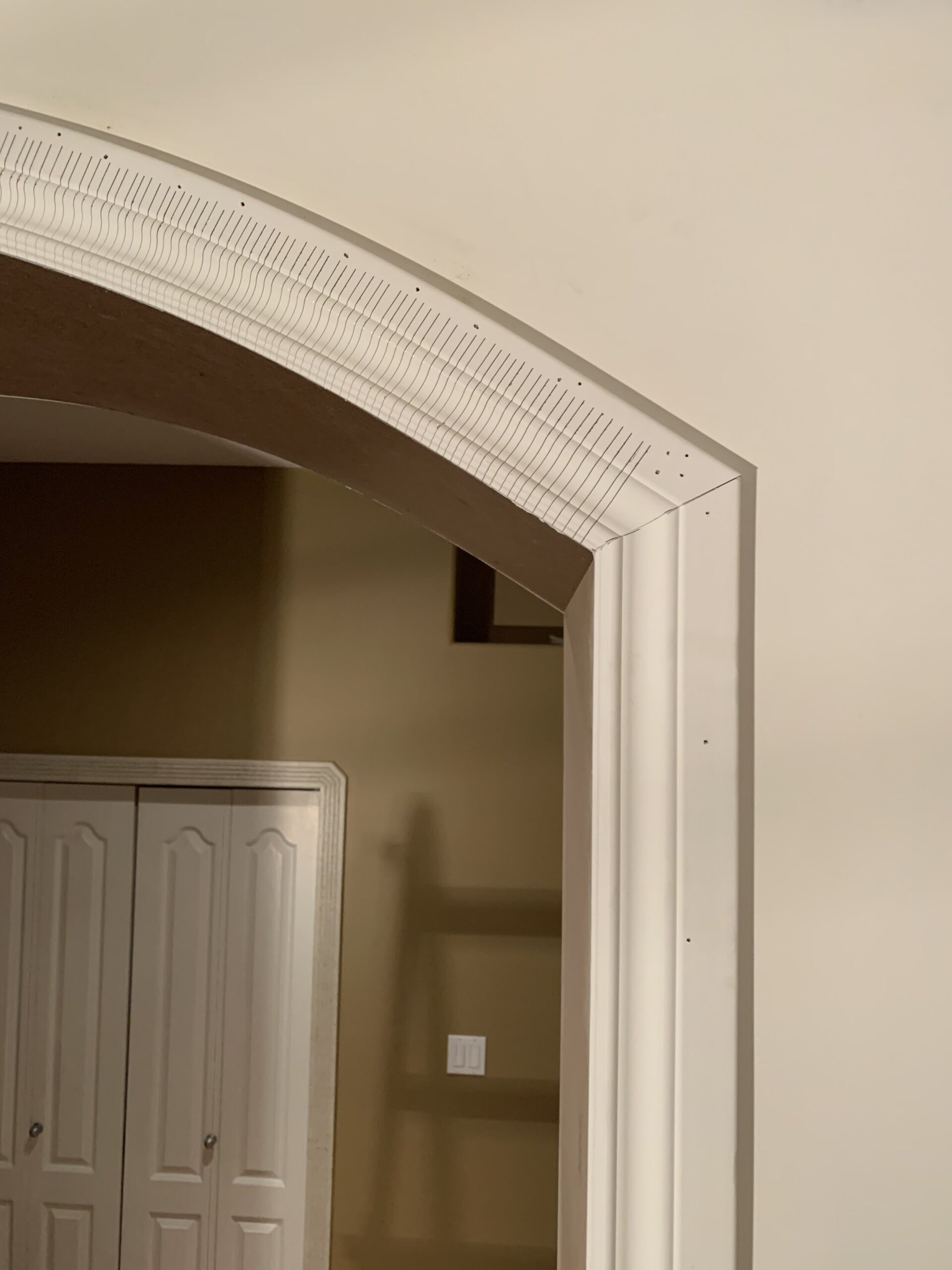 relief cuts on curved portion of trim on an arched doorway meeting up with the vertical trim at a mitered corner
