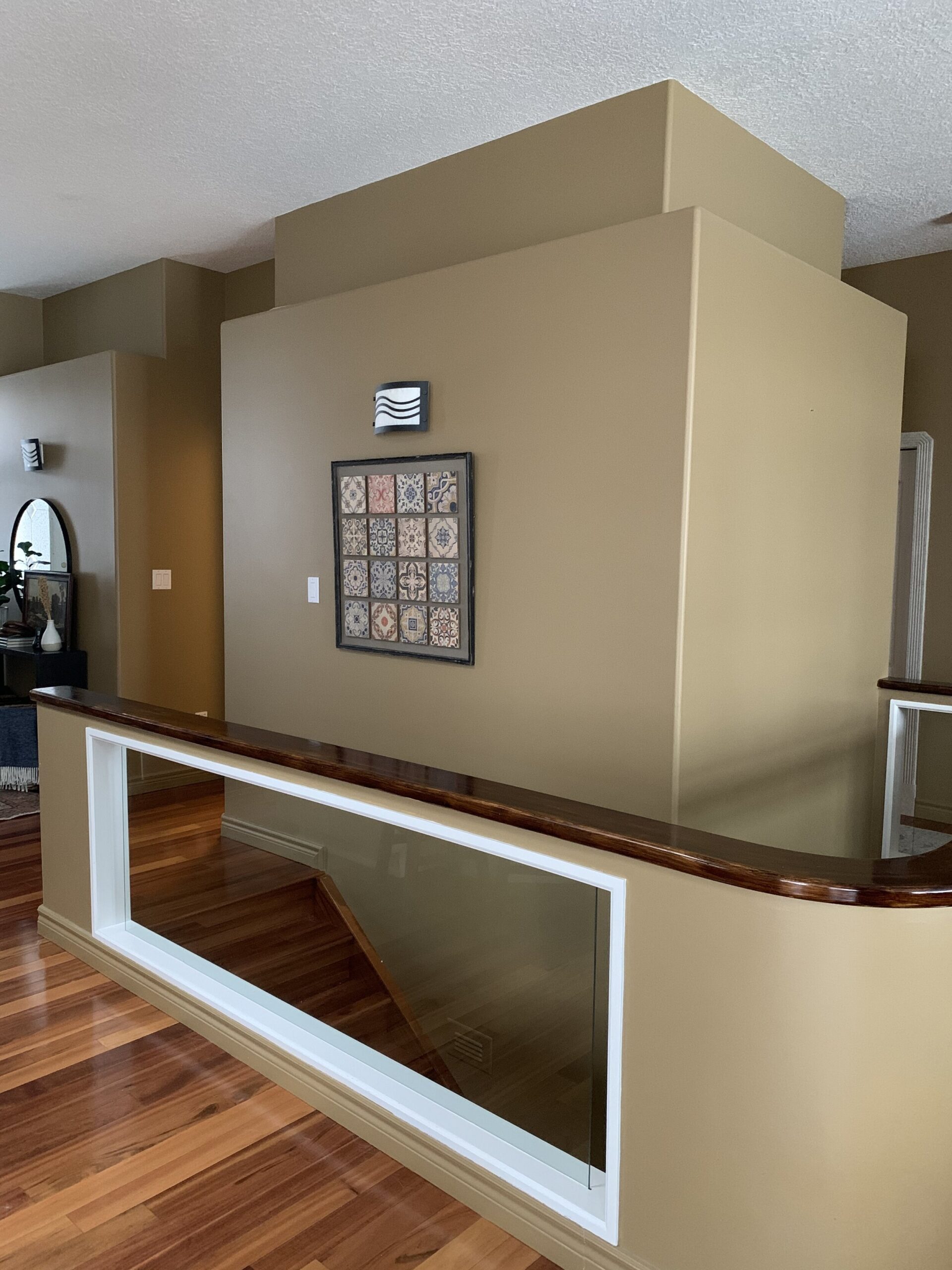 stairwell with cut out openings with glass in a pony wall railing and a ledge at the top of the wall 