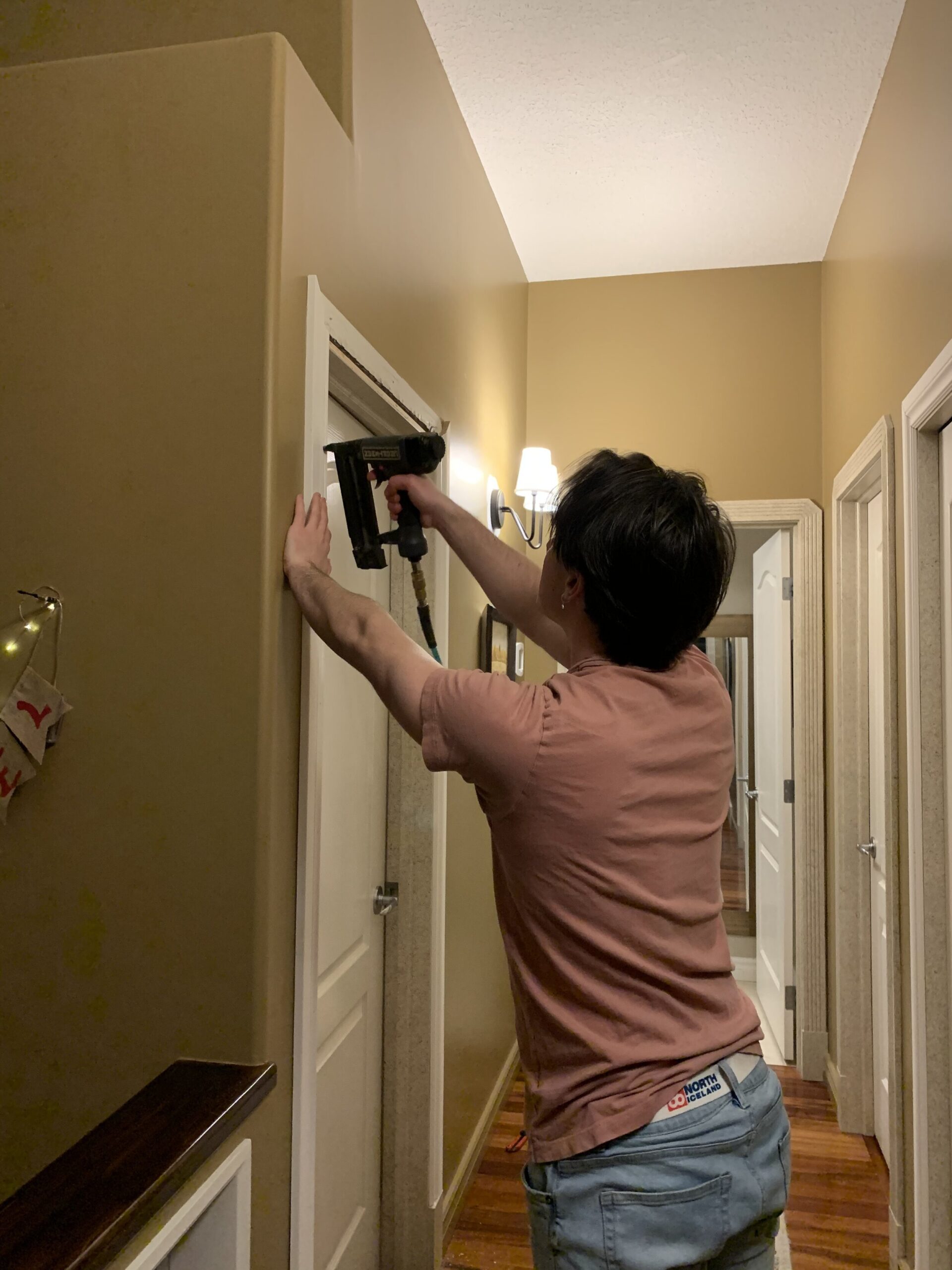 man nailing new trim to a doorway