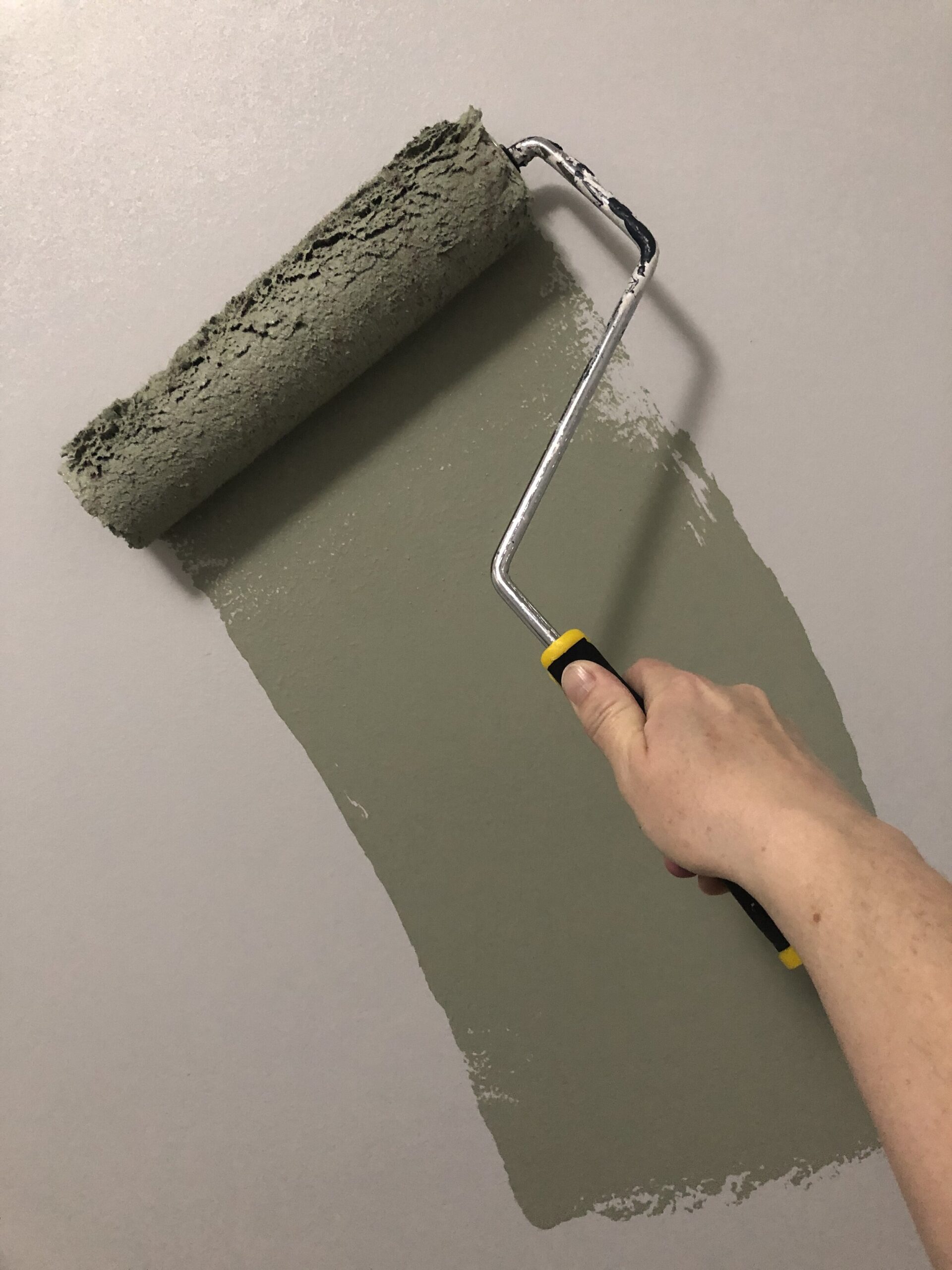 green paint being rolled on the wall