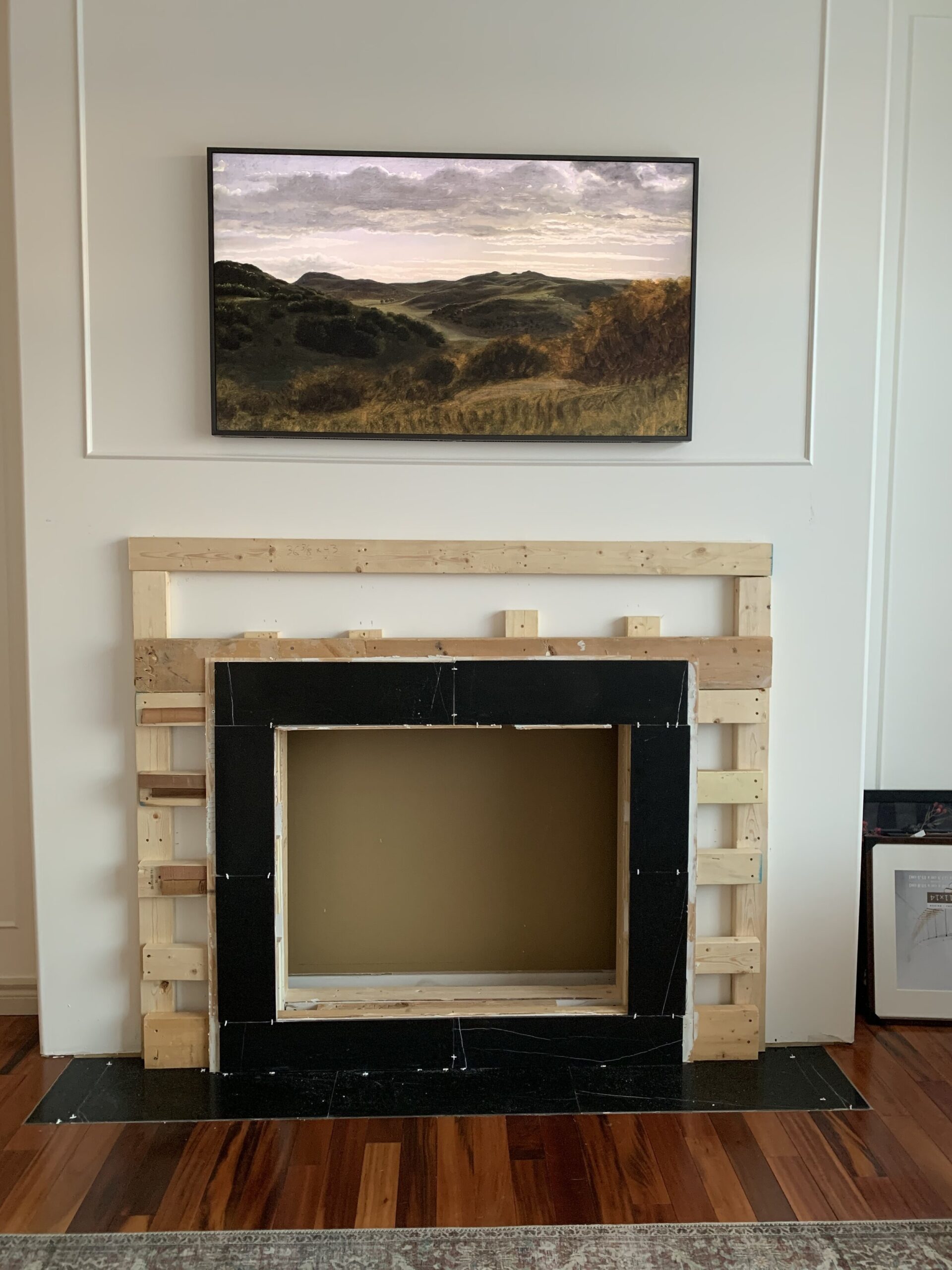 fireplace opening with framing in for mantel and black marble tile surround in 