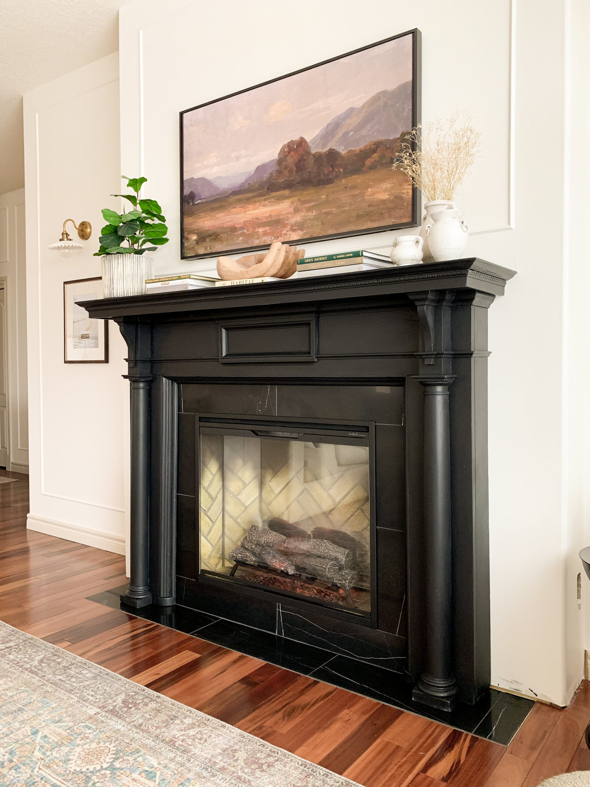 electric fireplace with black antique mantel and black marble surround and hearth with samsung frame TV above and styling on mantel