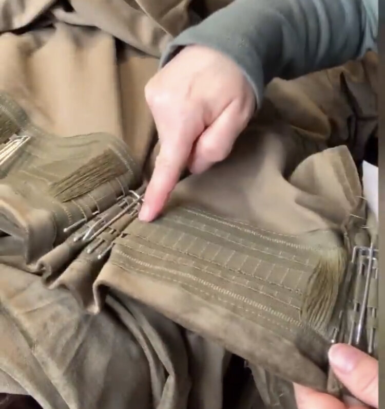 inserting triple pleat hooks into the back of green curtains