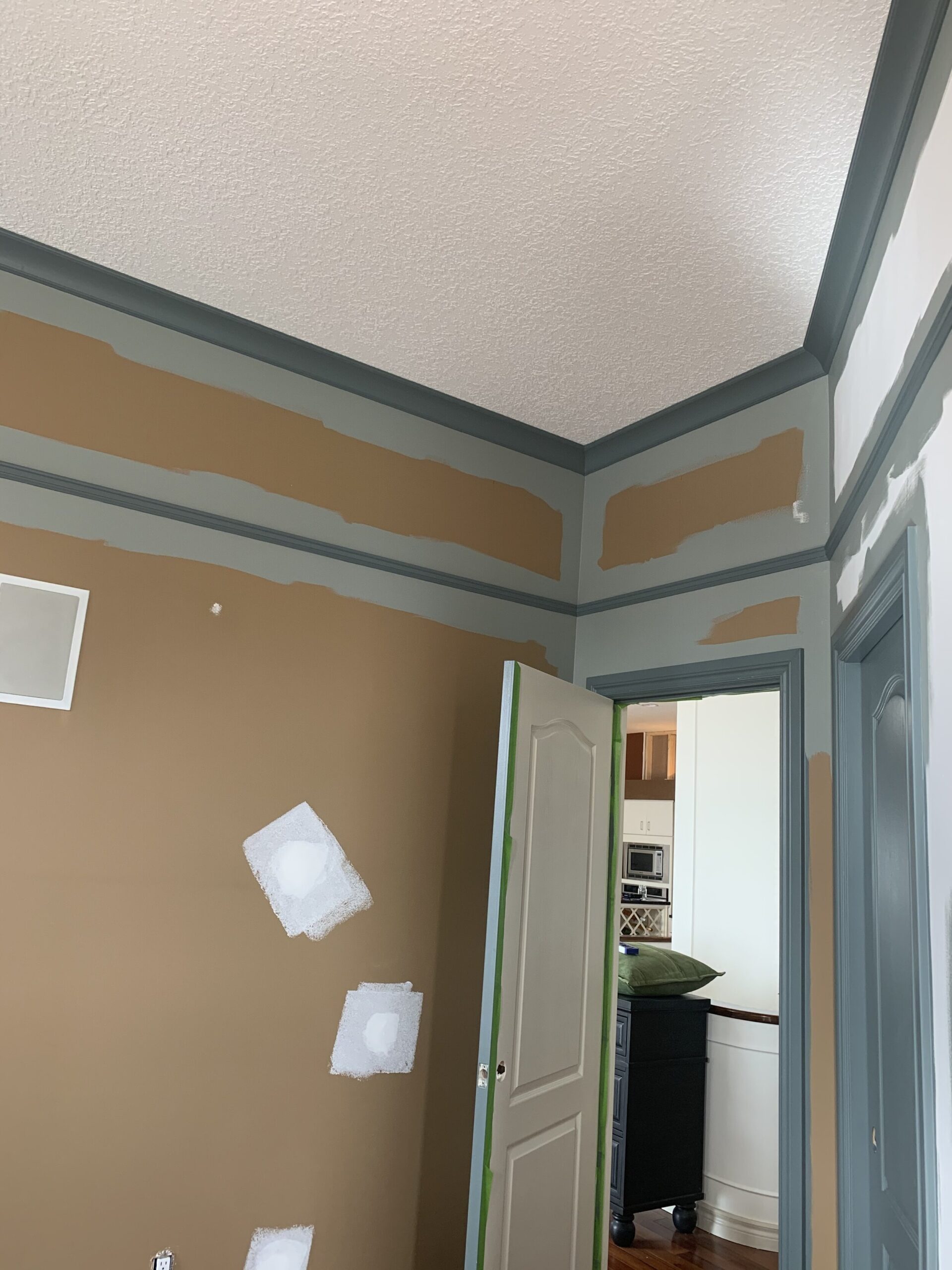 brown walls partially painted with green trim and edges cut in with green paint