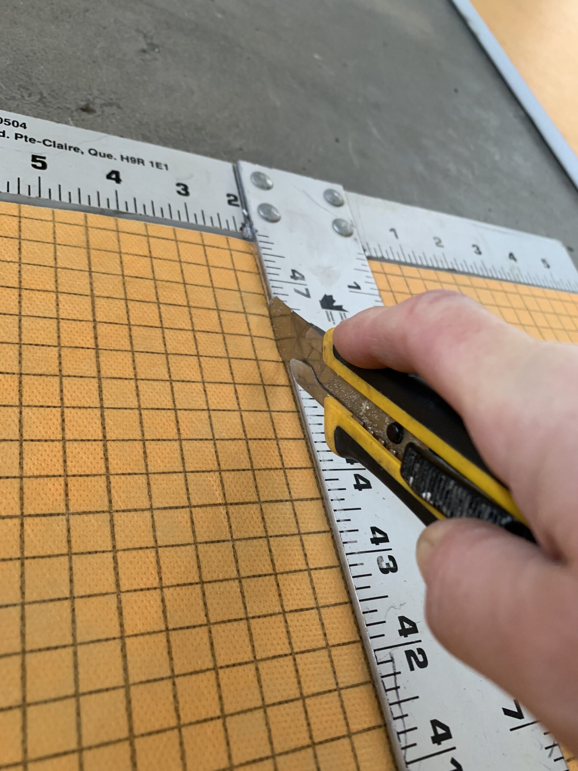 using a utility knife and straight edge to cut the kerdi board