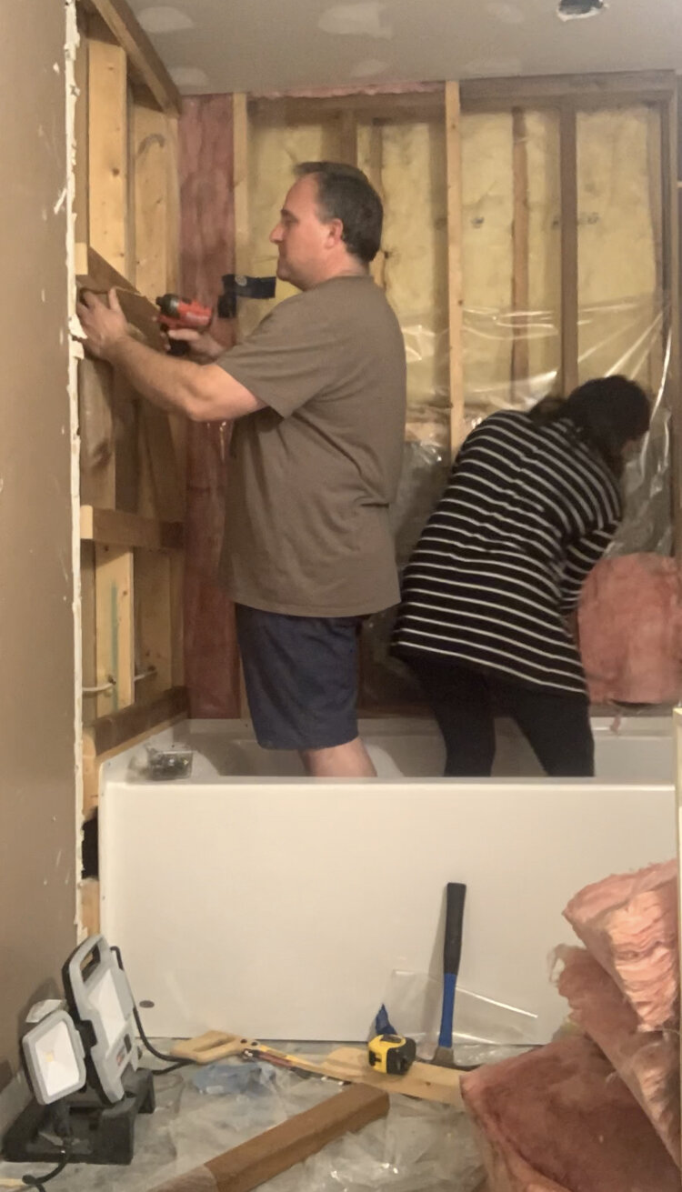 man and woman working on framing around a tub installing a frame for a niche 