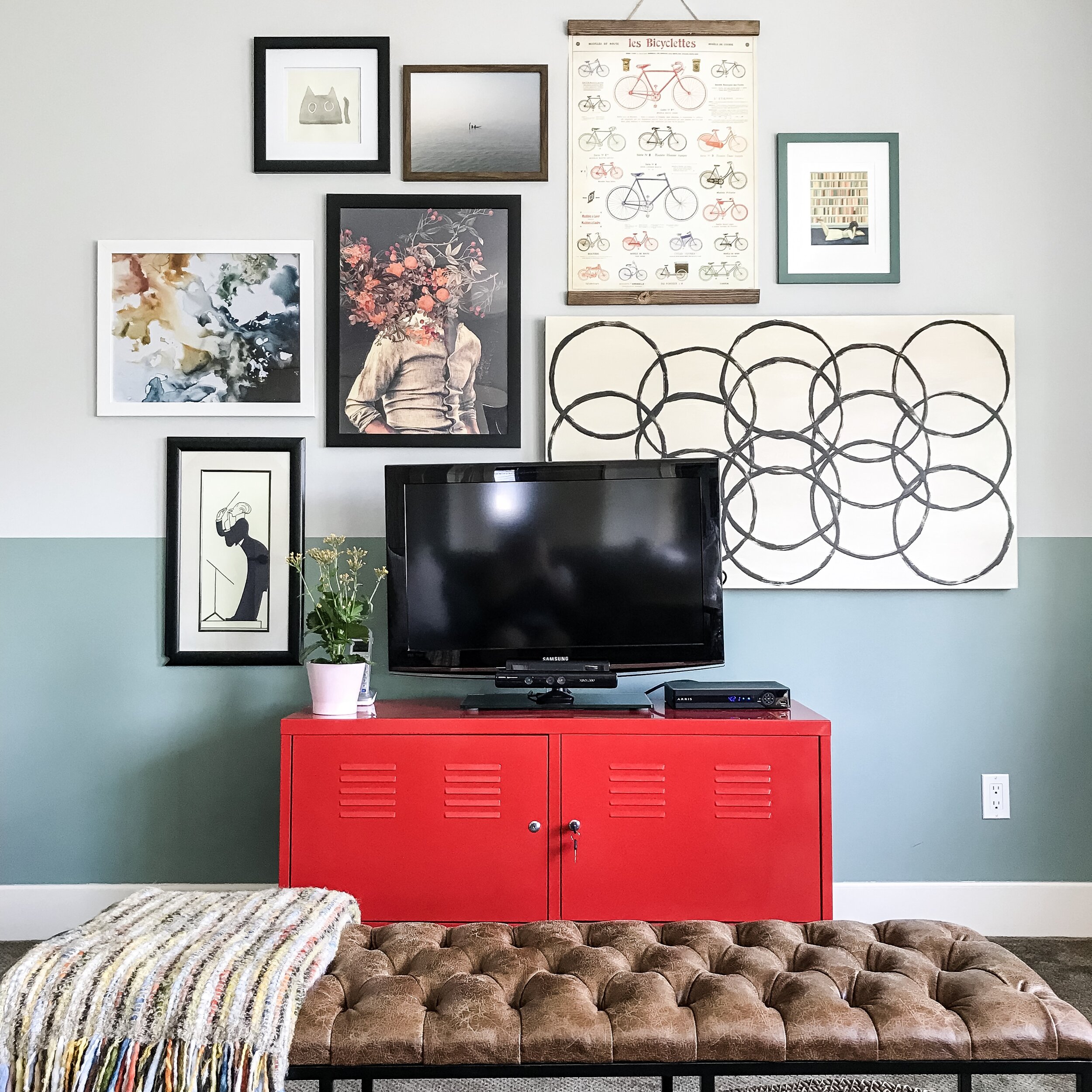red tv stand with tv on it with gallery wall installed around it, with various pieces including a large DIY art with circles 