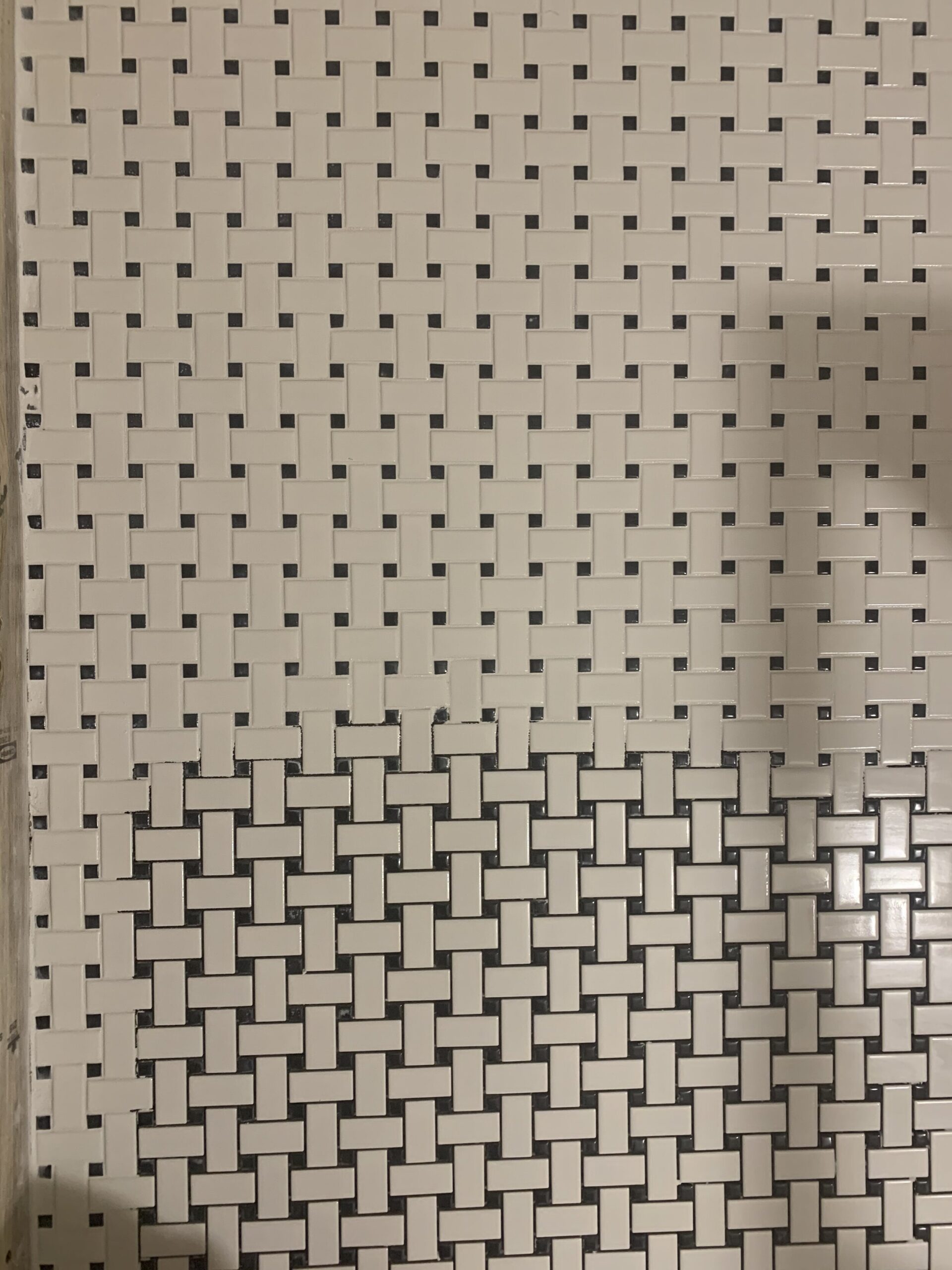 Black and white basketweave ceramic tile with grout half finished