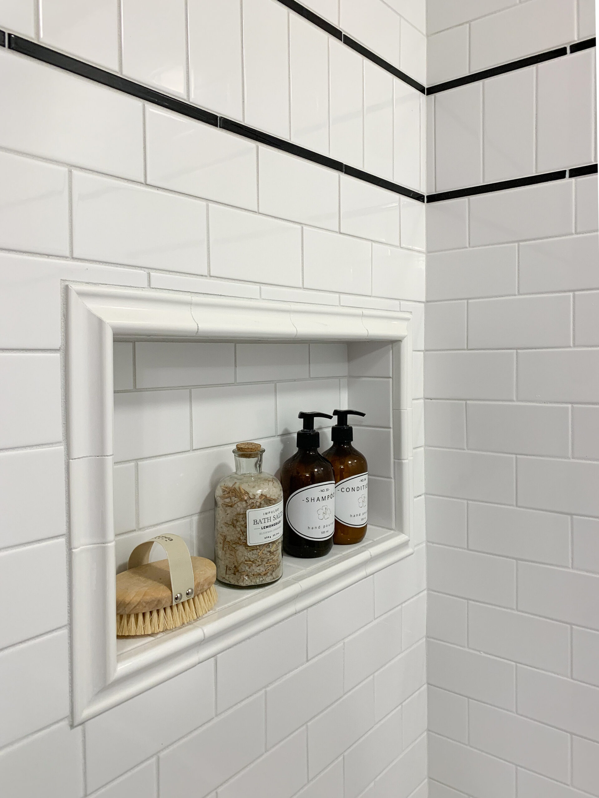 Custom subway tile installation with black pencil tile double trim and a niche framed out with bullnose tile