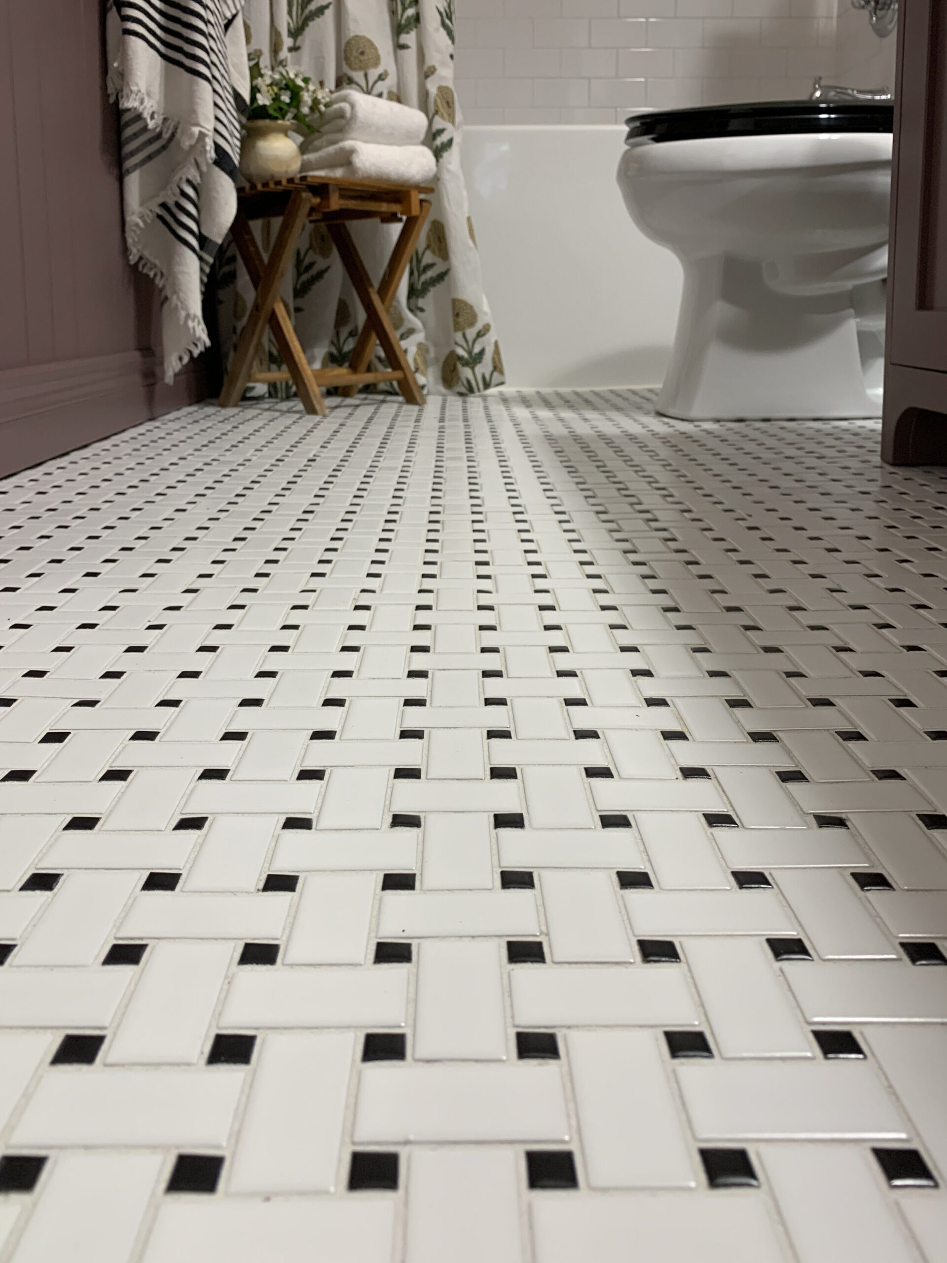 Basketweave ceramic tile floor in black and white in a purple bathroom