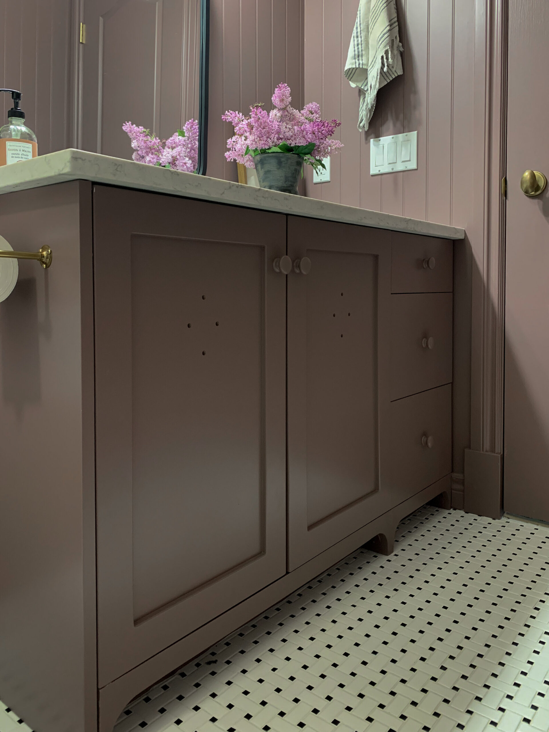 Purple vanity with vent holes in shaker style doors, flat front drawers with painted knobs, and cutsom feet as a toe kick