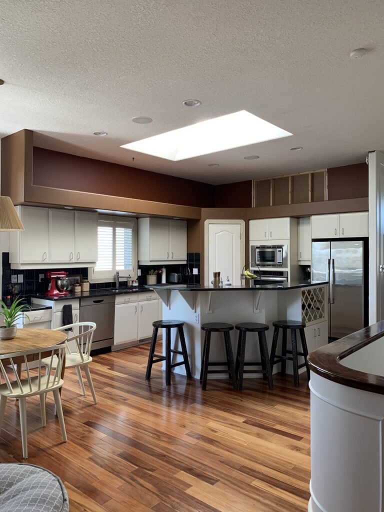 before kitchen with drywalled soffit, white cabinets and angled island with raised eating bar and a corner pantry