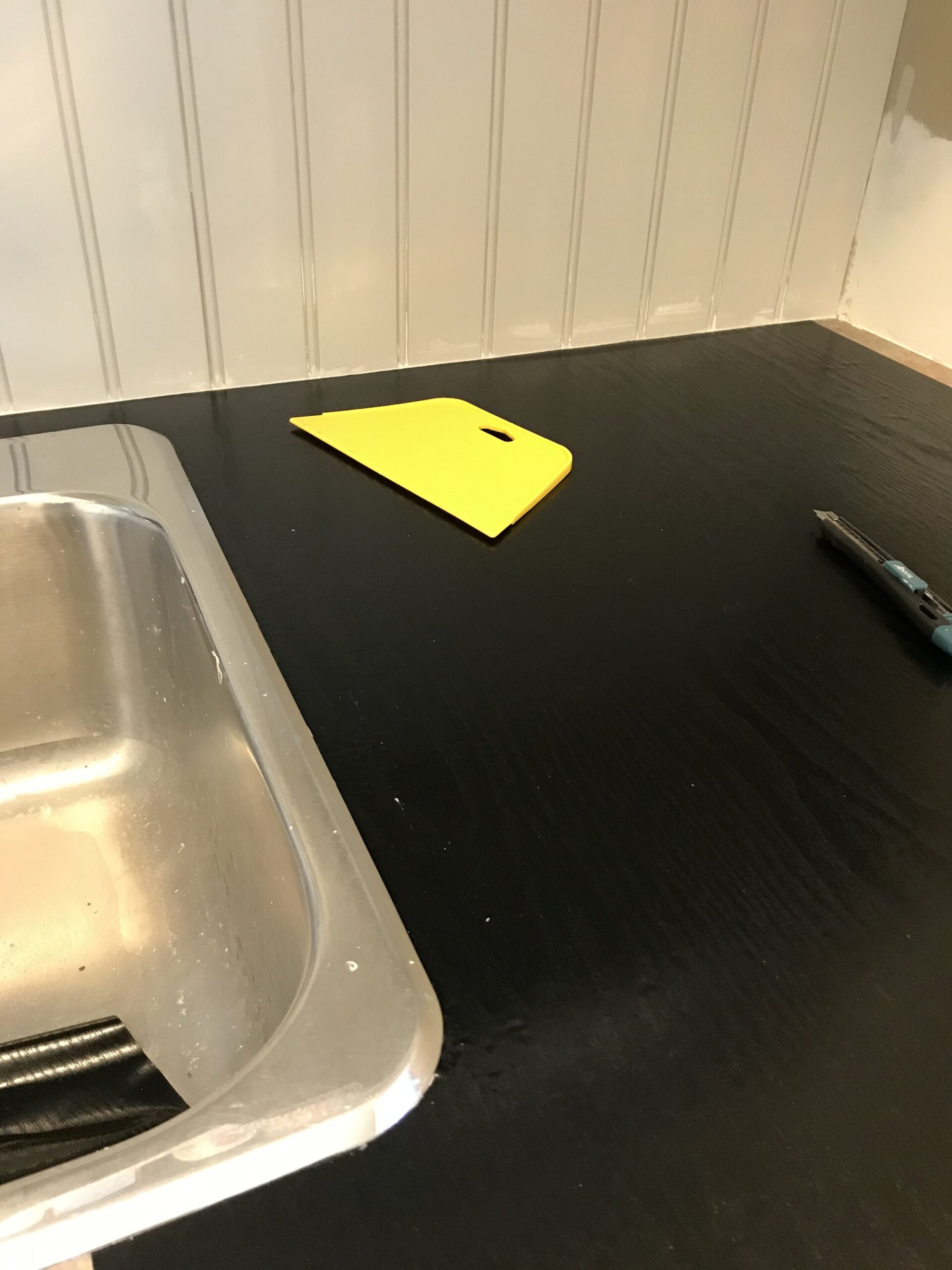 black contact paper on a countertop with a wallpaper smoother in the background