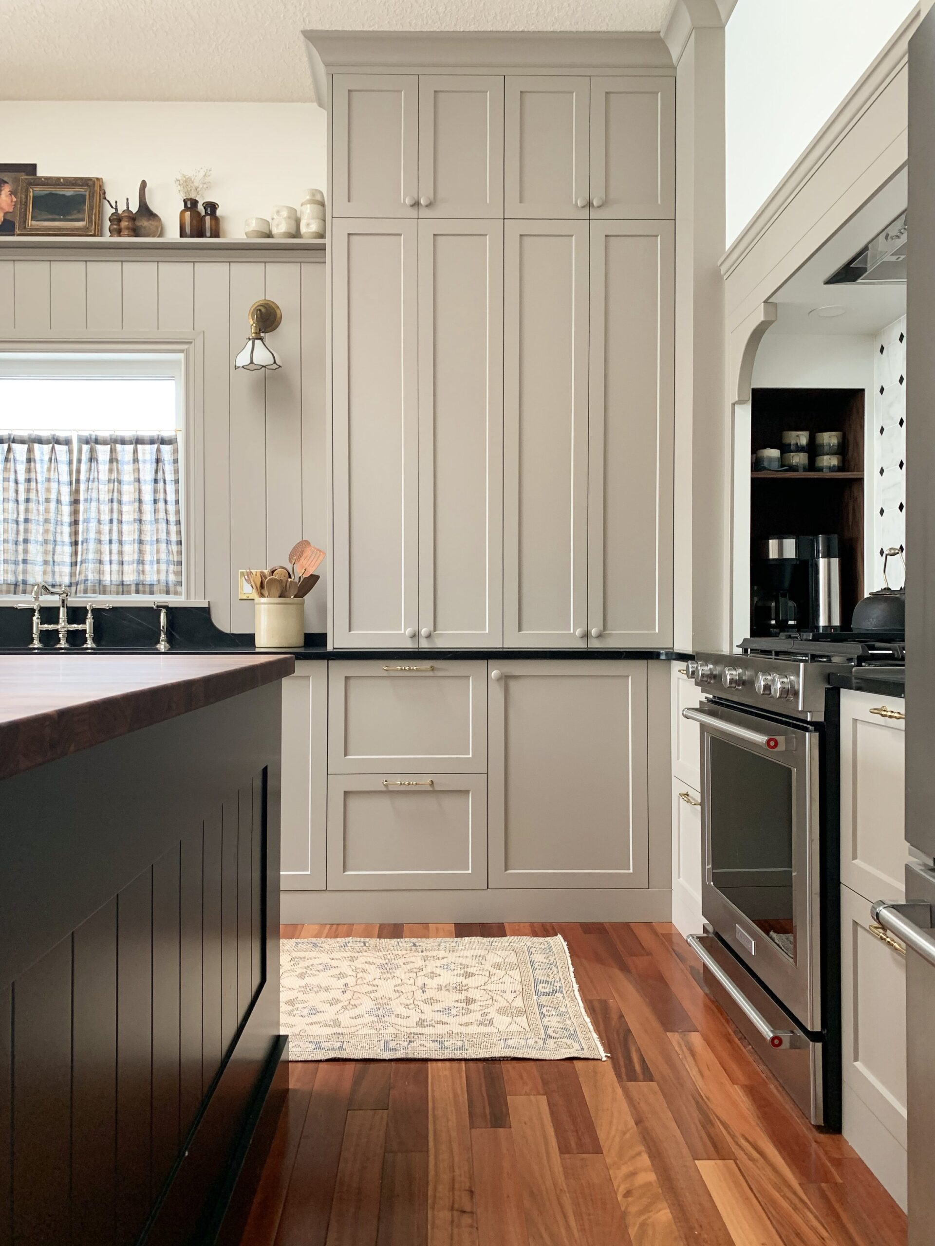 modern traditional kitchen with beige cabinets with stacked uppers and built in custom range hood, black island
