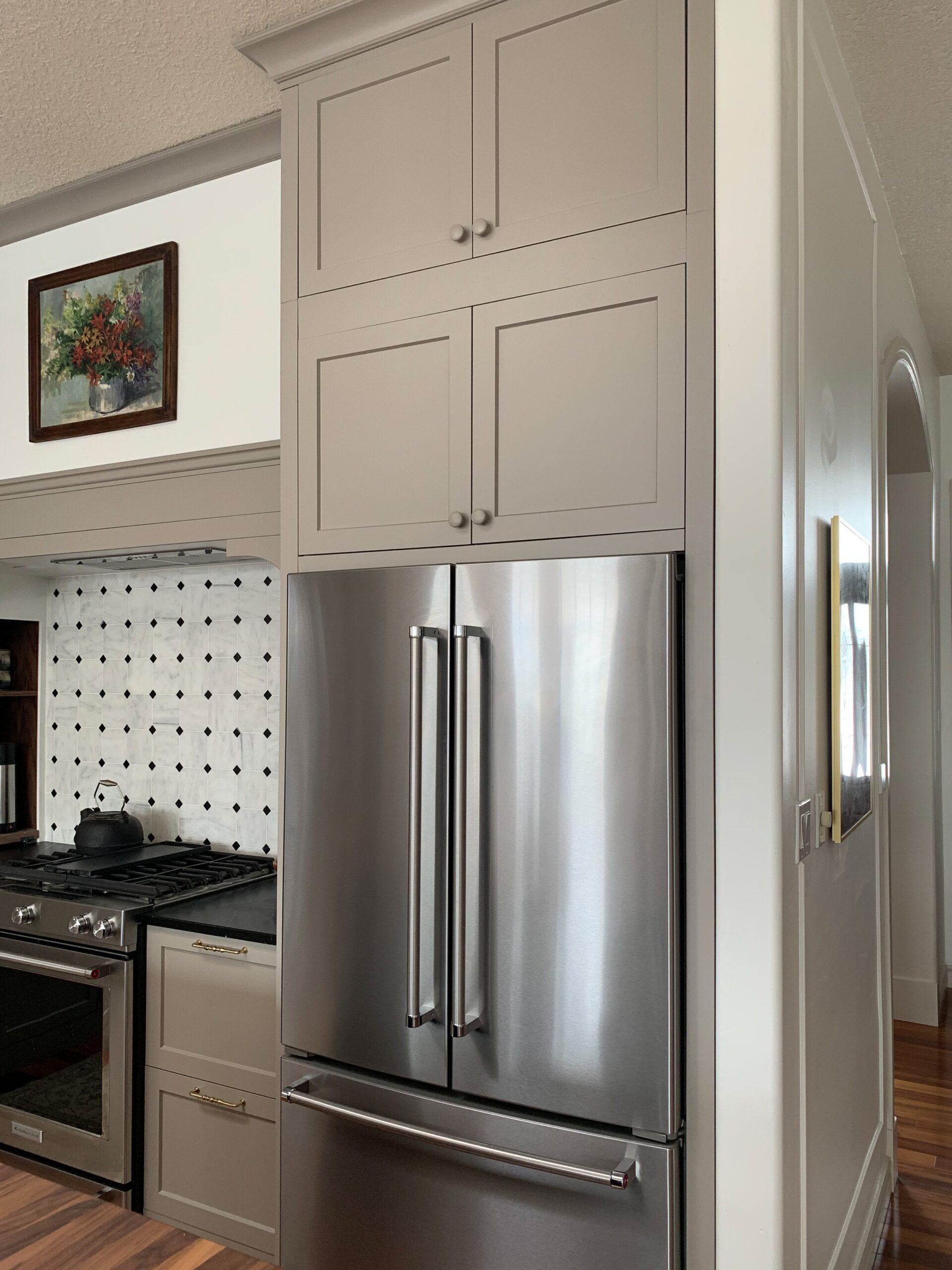 Stacked cabinets over fridge built out to make fridge look built in with beige cabinets and stove nook beside