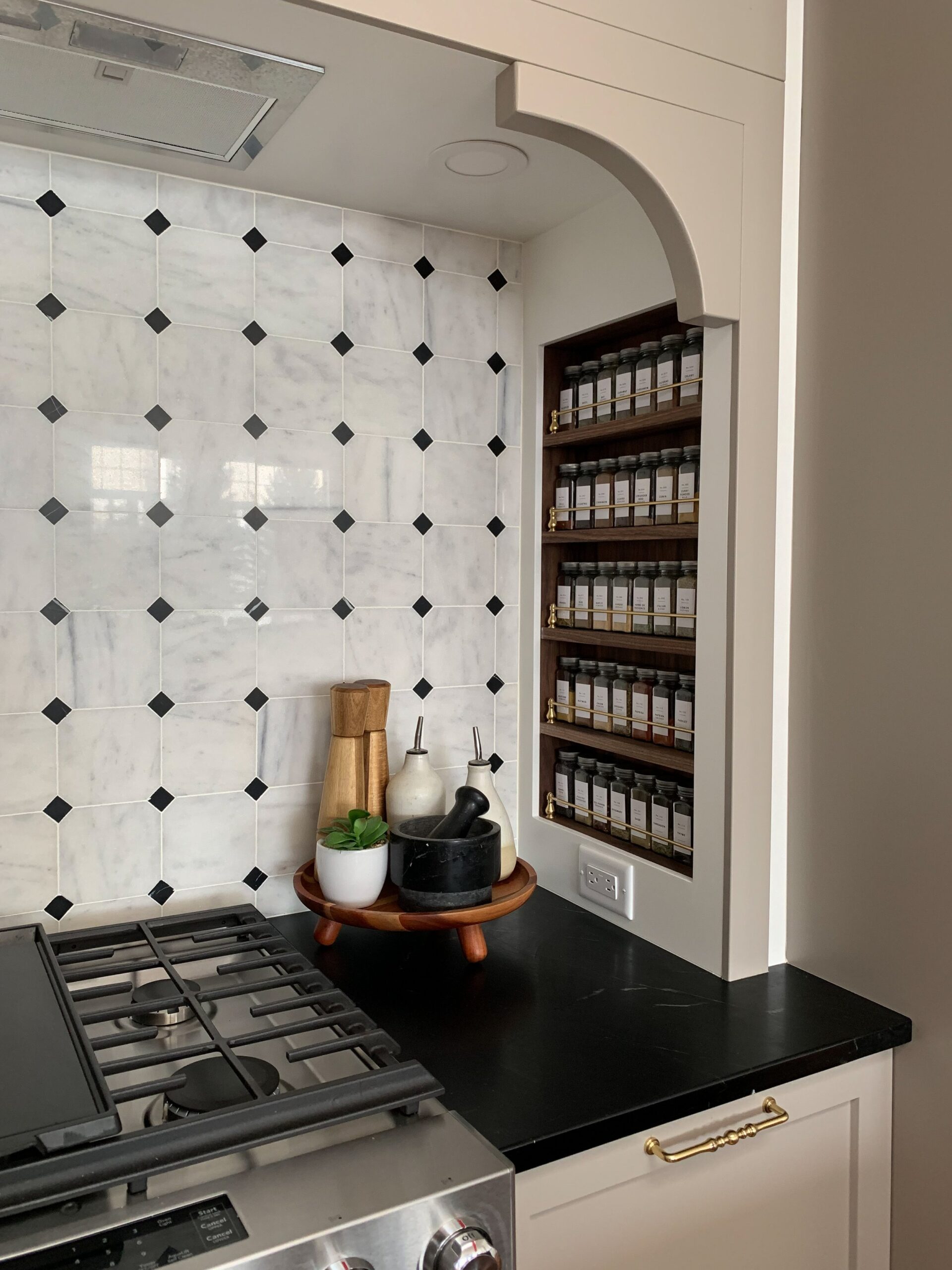 built in walnut spice rack on the side of a stove nook with soapstone counters and marble backsplash