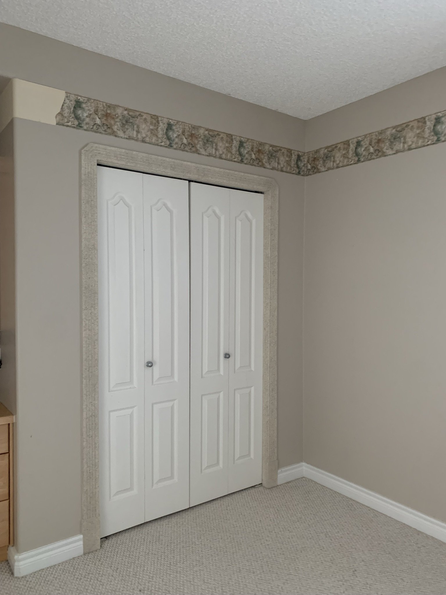 bifold closet doors with partially removed wallpaper border above