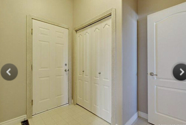 Room with beige walls and several doors and linoleum floor