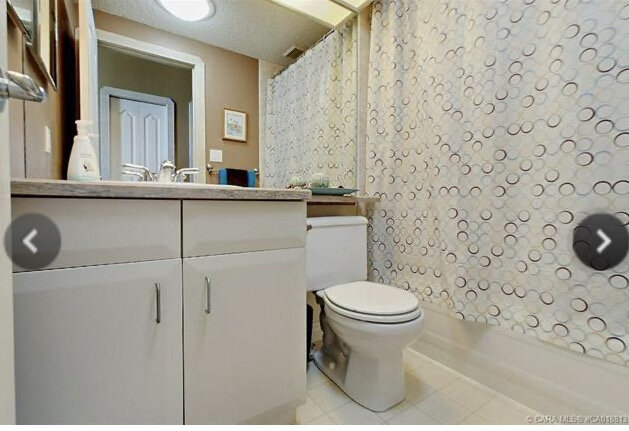 bathroom with white cabinets, linoleum floors, laminate counters, full wall mirror and shower curtain over tub area