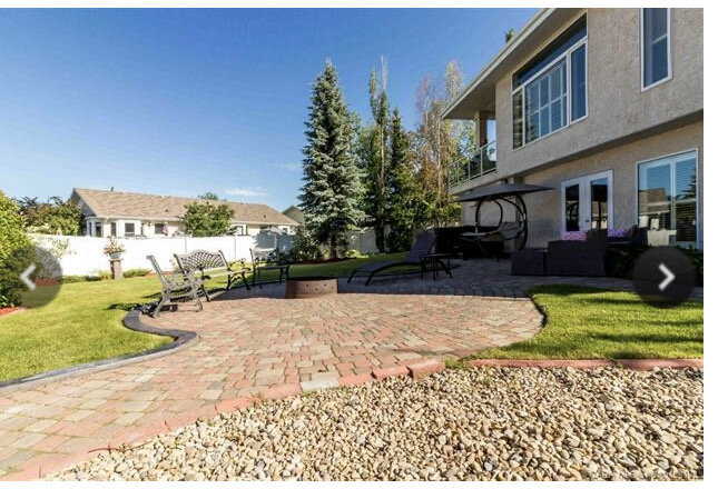 Stone patio with firepit and trees in background, house on the right