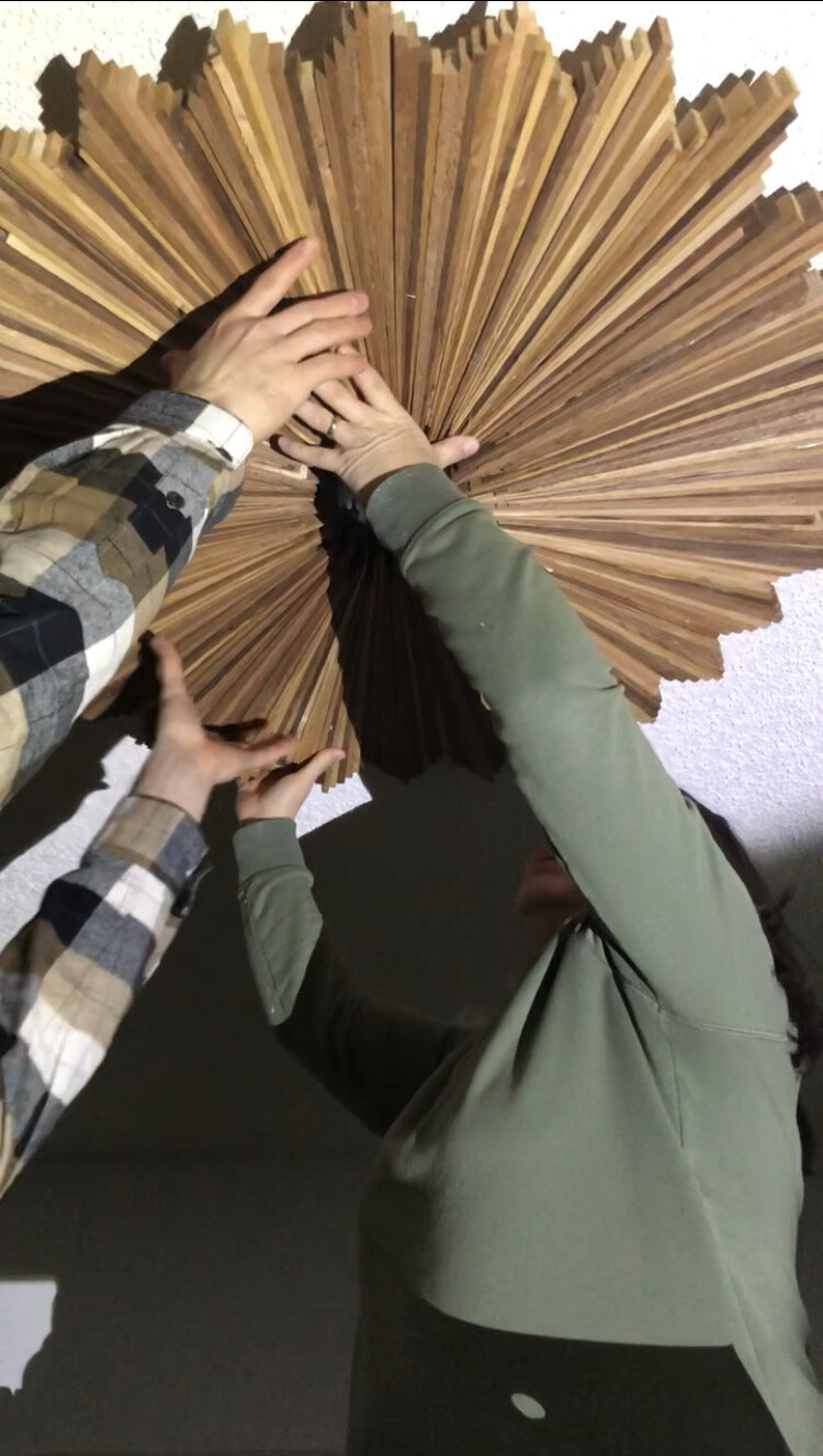 two people lifting cedar light fixture up to ceiling