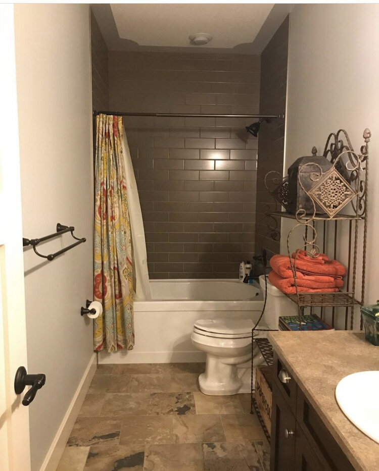 bathroom with high ceilings and short shower curtain, brown subway tile, greay walls and slate floor