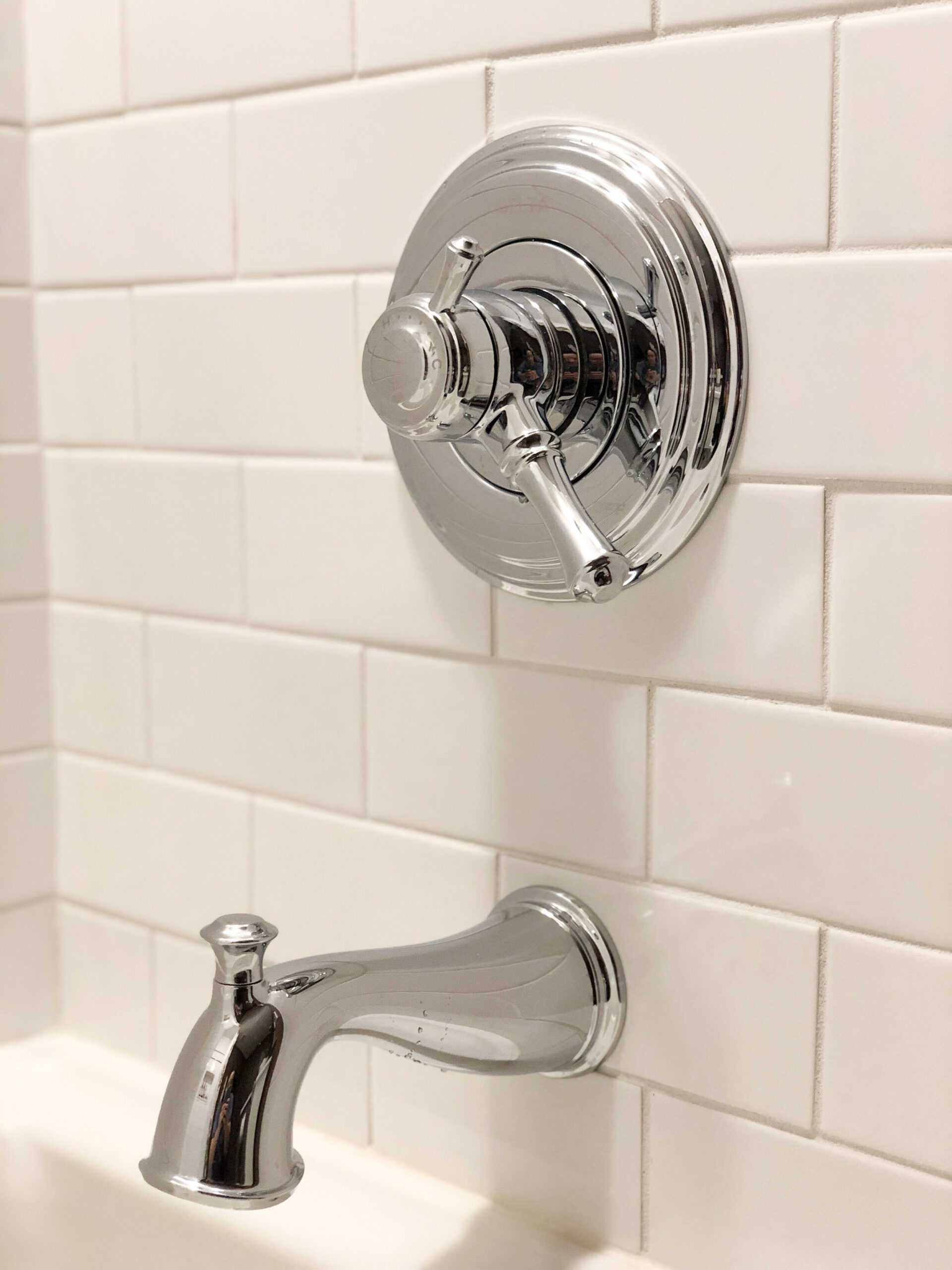 Tradtiional style chrome bathtub fixtures on a white subway tile wall