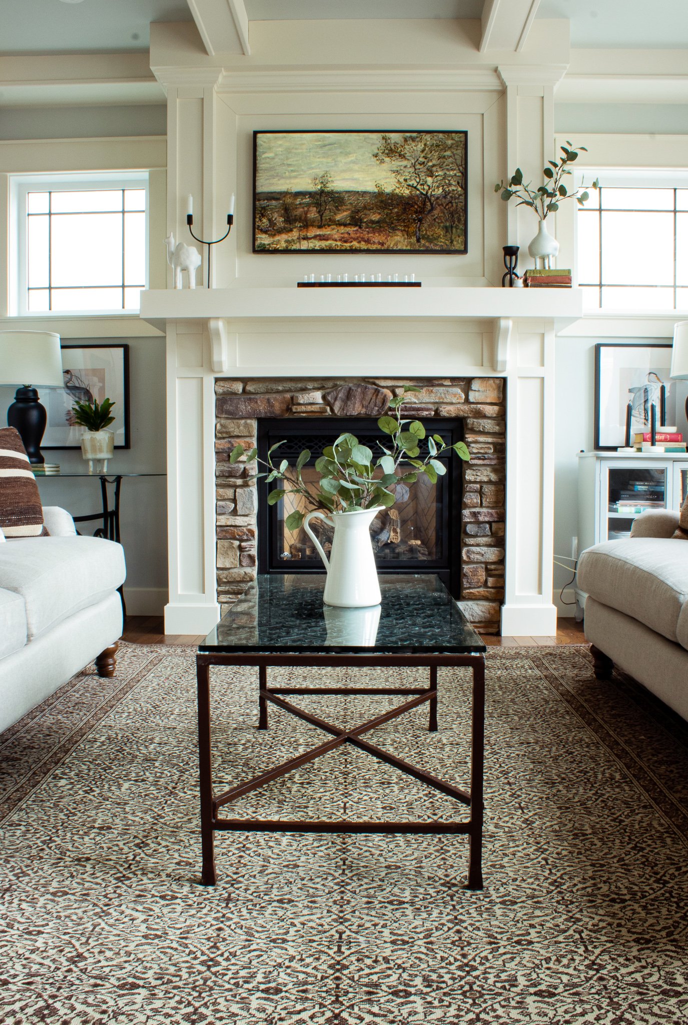 Vintage Rug in a white dining room with two couches facing each other and a stone fireplace with custom surround