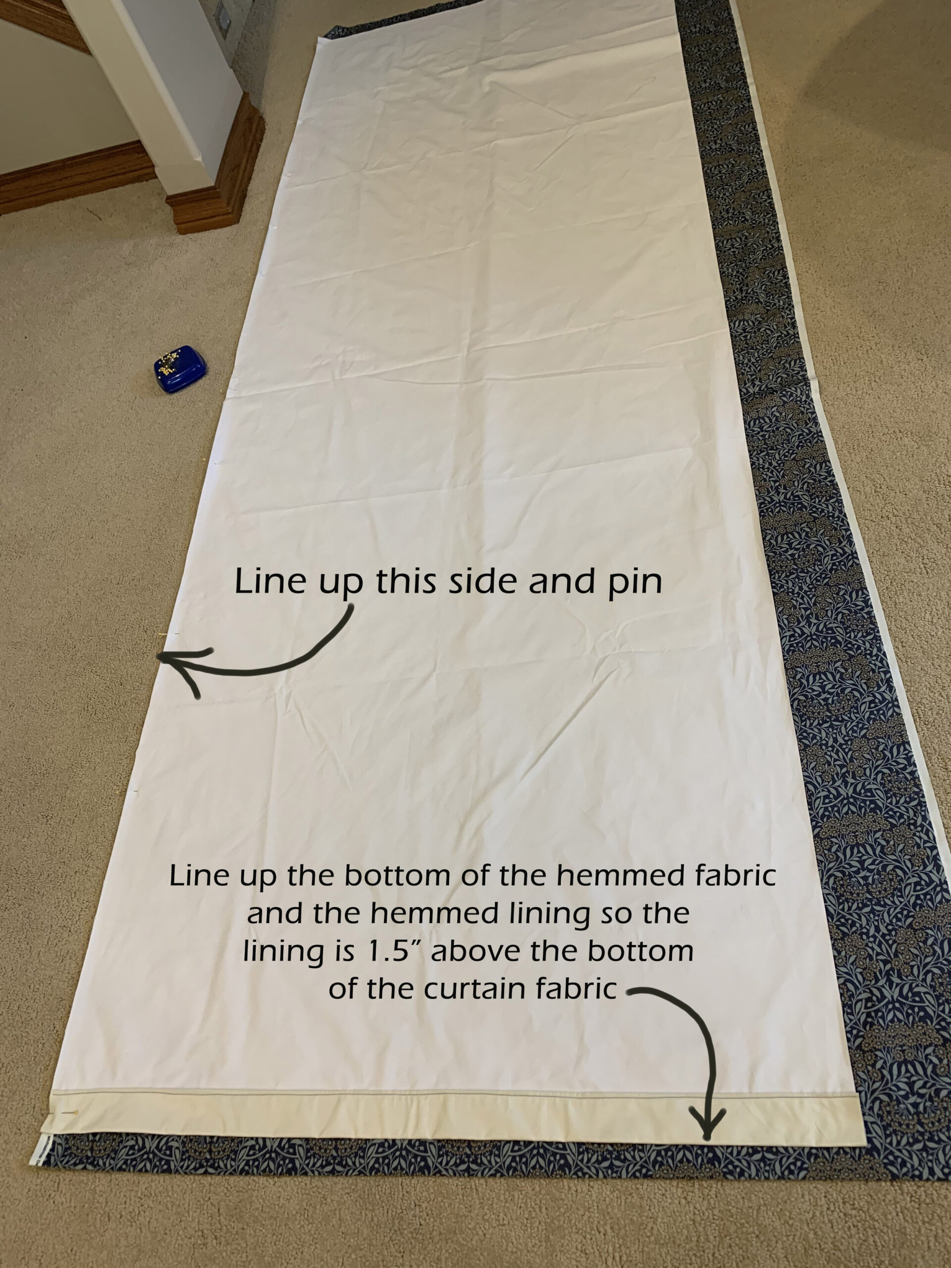 fabric laying on ground showing lining laying on top and lined up on one side and showing the lining 1.5" above the curtain fabric