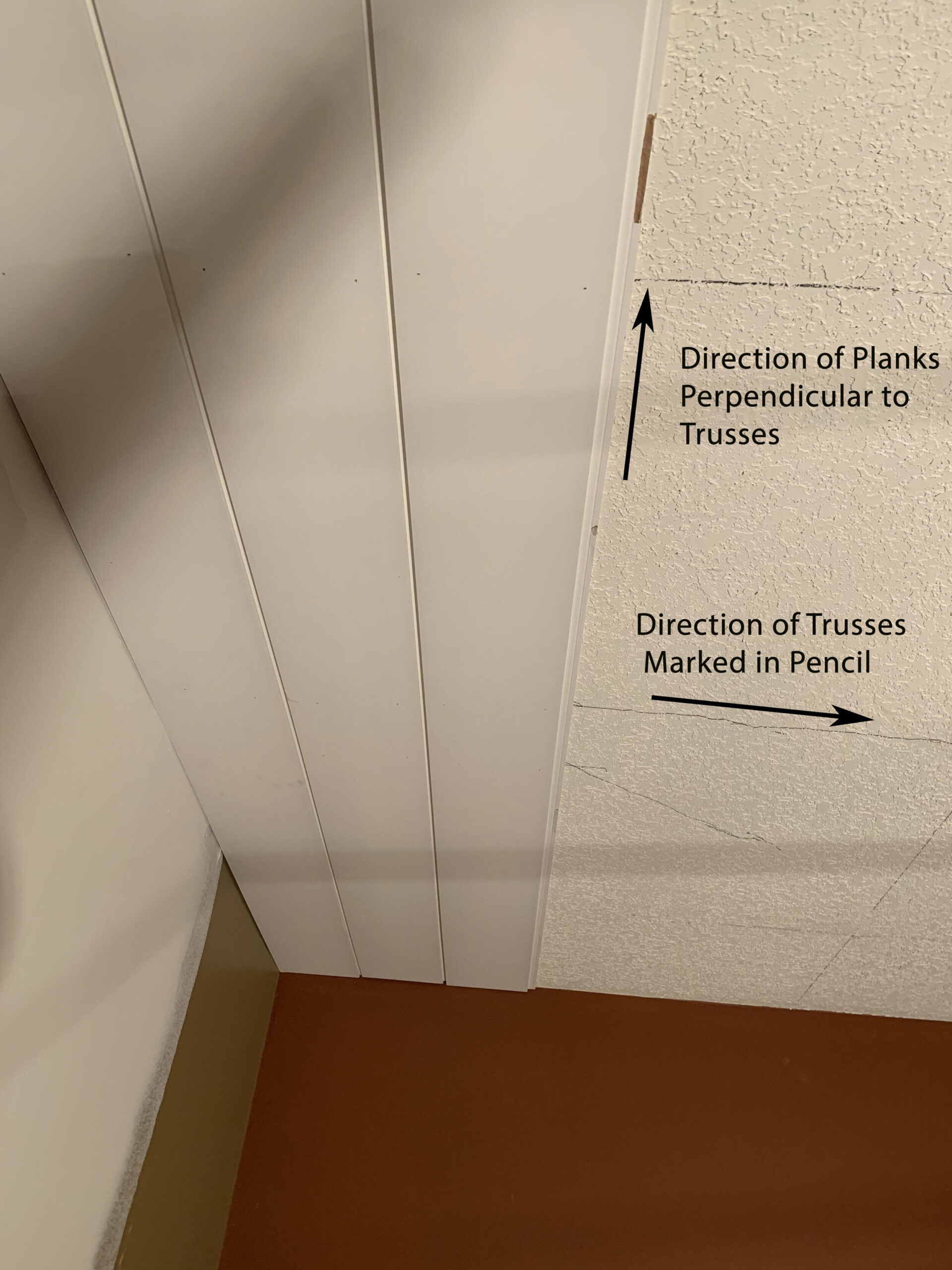 a ceiling with a few planks in place and some arrows showing the direction of the trusses going perpendicular to the planks