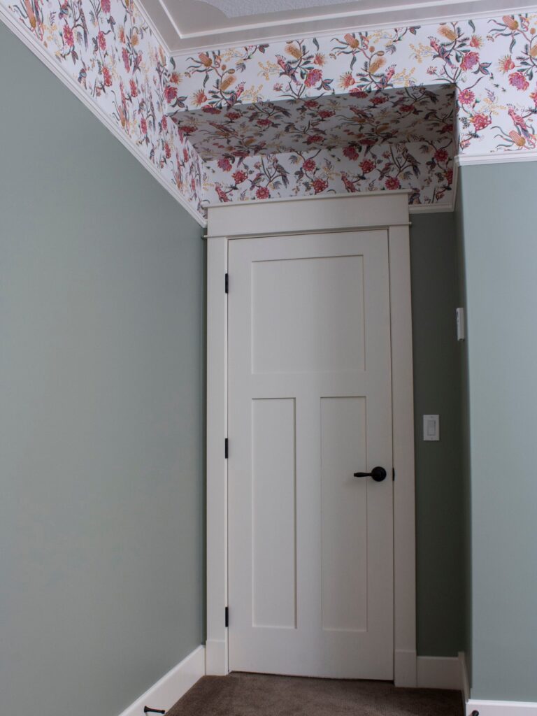 wallpaper installed on a bulkhead and on the top third of a room with green walls below