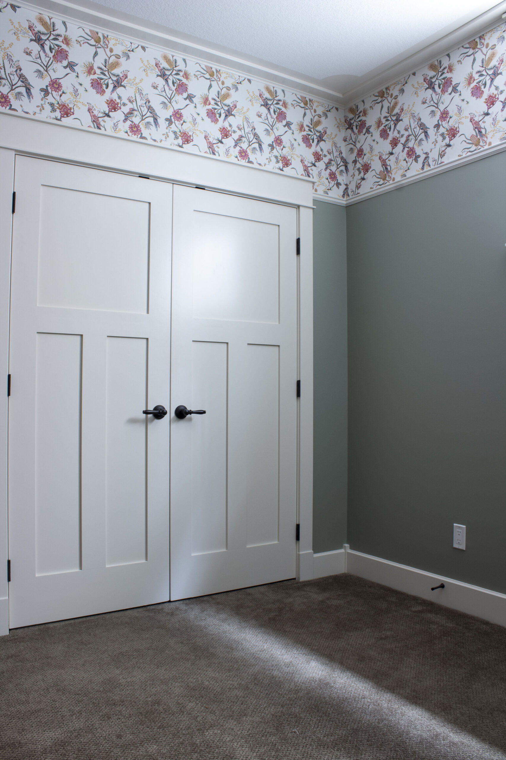 closet doors in white with white trim and wallpaper installed above a picture rail moulding, with green walls below