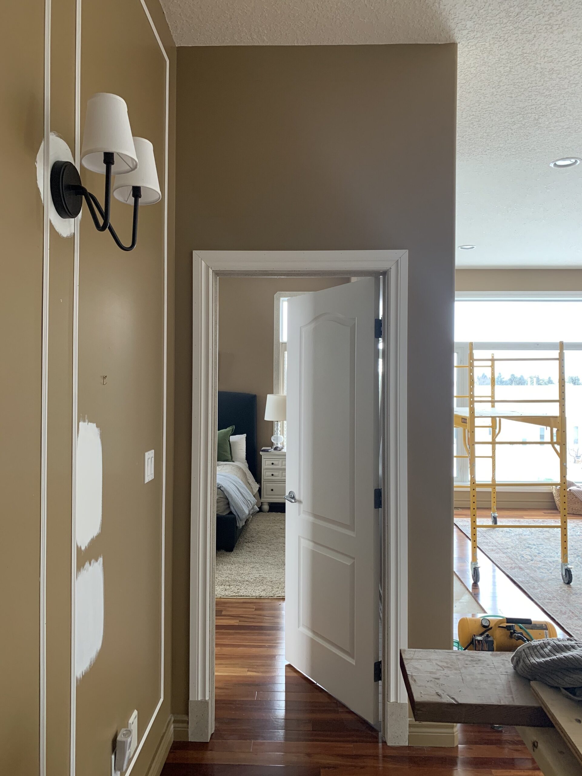 image showing hallway with brown walls and some patches of test paint, added box trim and new black sconces