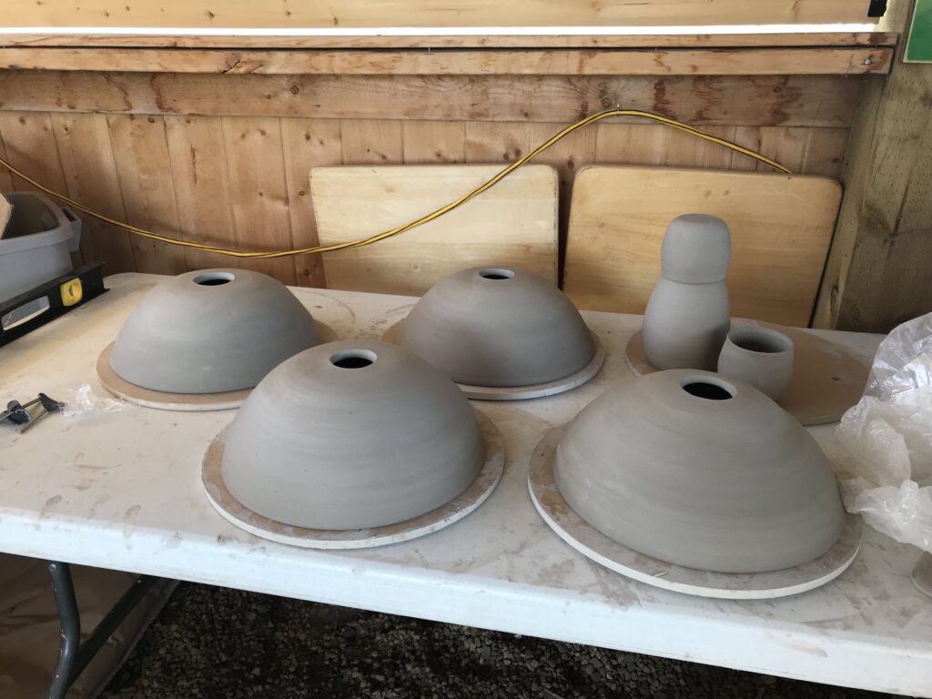 ceramic shades being made with several shades out on a table drying