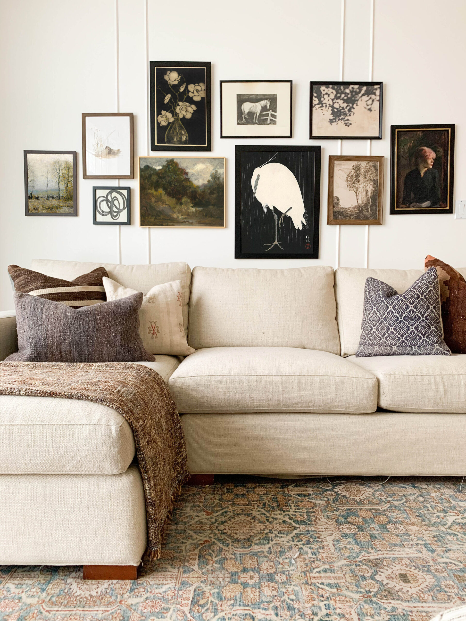 vintage art gallery wall over a couch with pillows and a vintage style rug